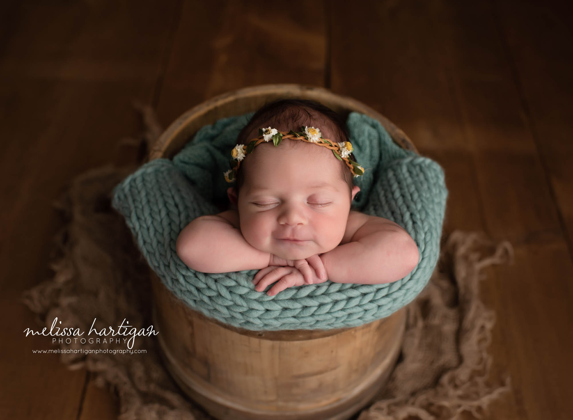 baby girl posed in woo0den bucket with teal layer and flower headband