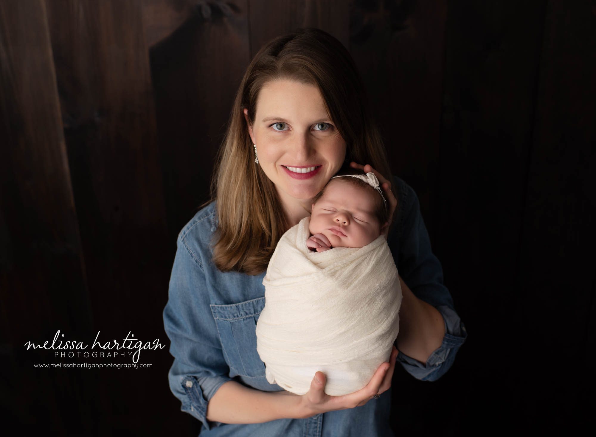 mom holding wrapped baby girl in newborn session