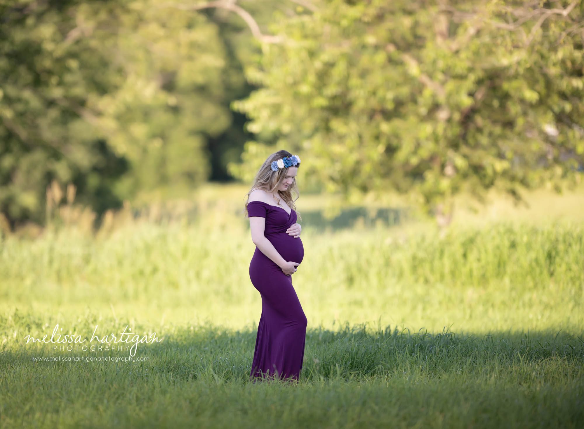 pregnant mom holding baby bump standing in field