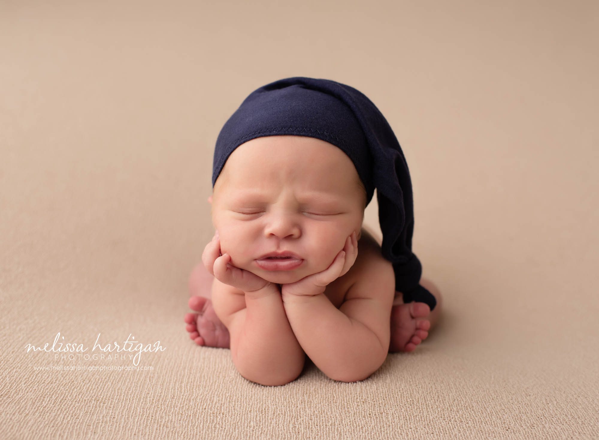 baby boy posed groffy pose with navy blue sleepy cap on