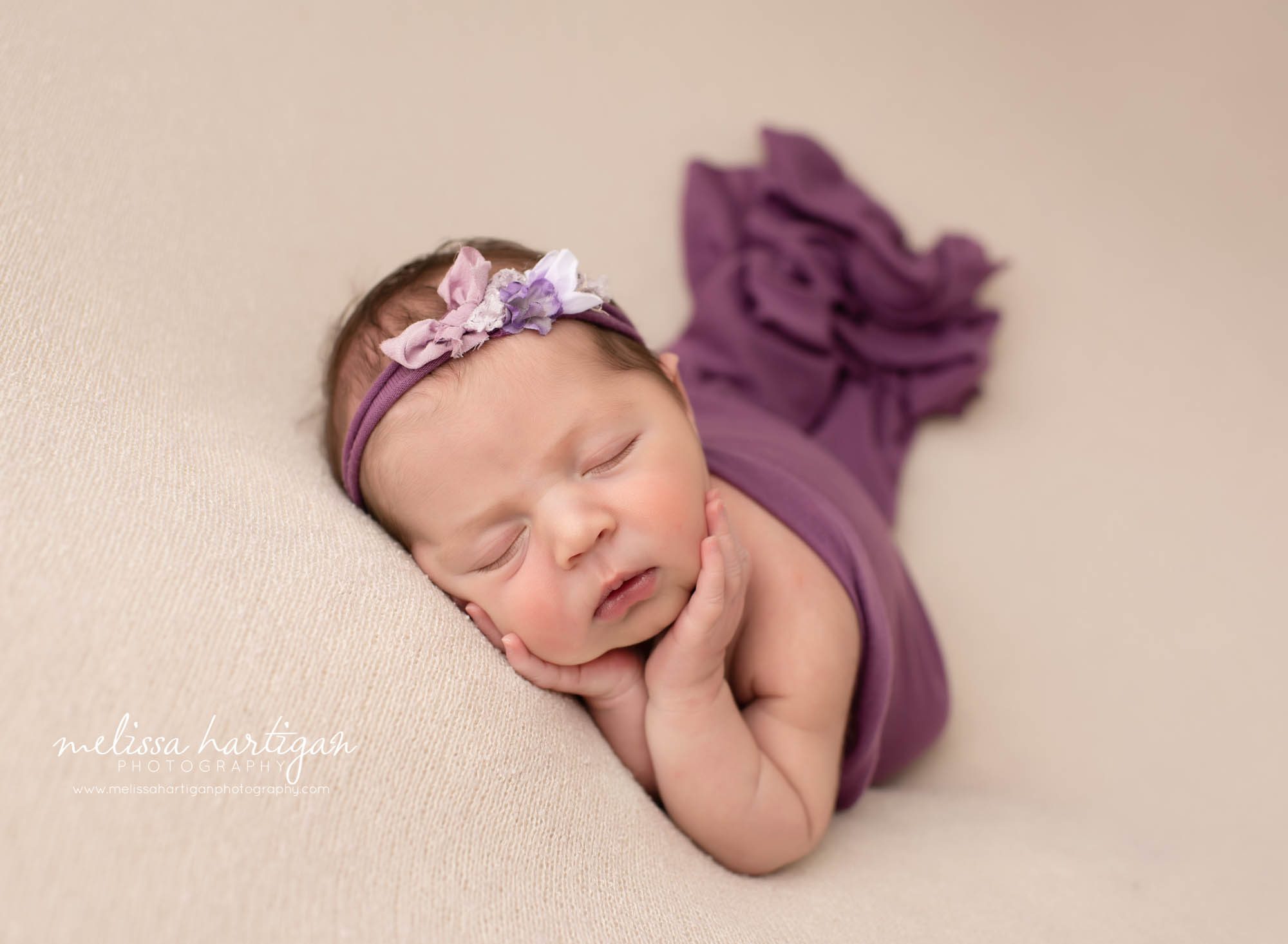 baby girl posed on beige with purple layer wrap and purple headband
