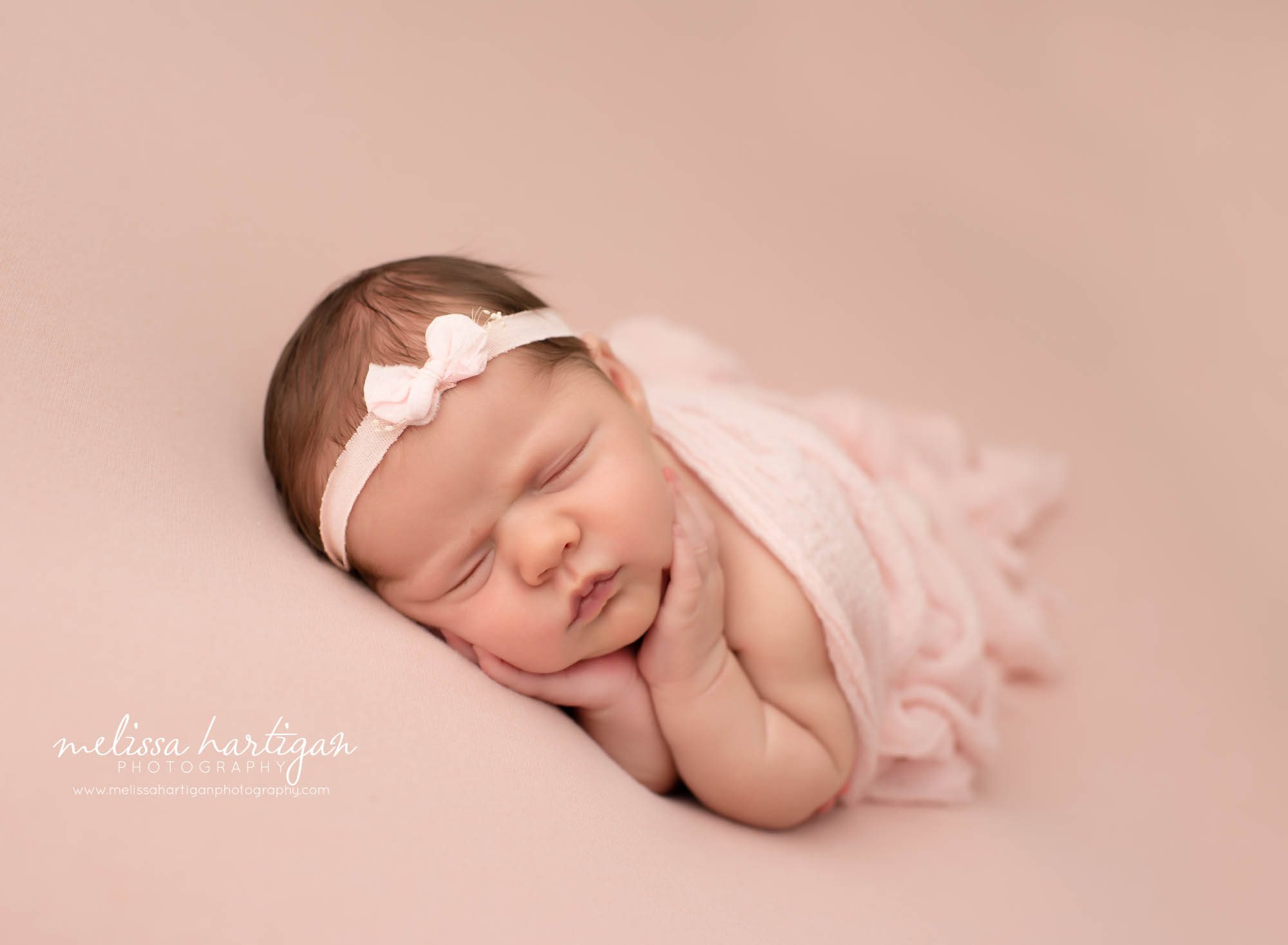 newborn baby girl posed with light pink wrap posed on pink backdrop with pink bow headband Newborn photography CT