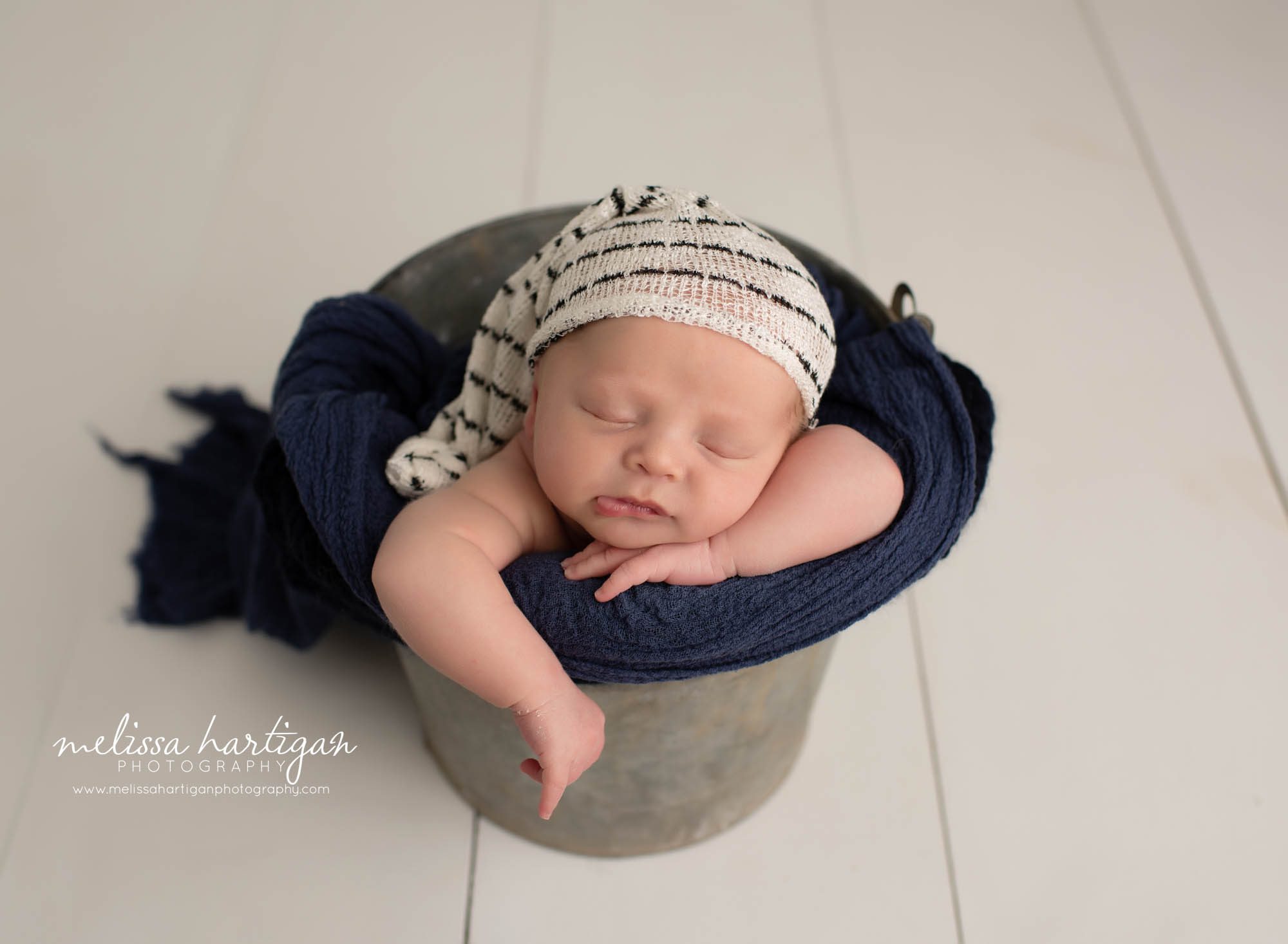 baby boy posed in metal bucket with sleepy cap on
