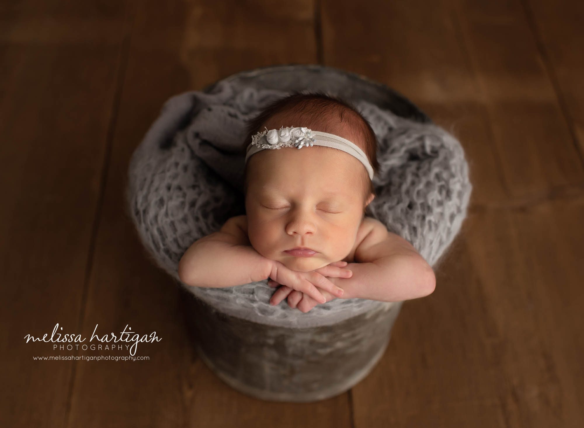 baby girl posed in bucket with gray knitted wrap and gray floral headband Glastonbury CT newborn photography