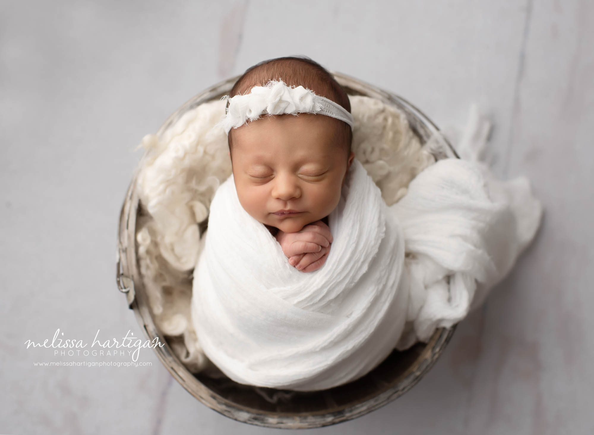 Newborn baby girl wrapped in white with white headband