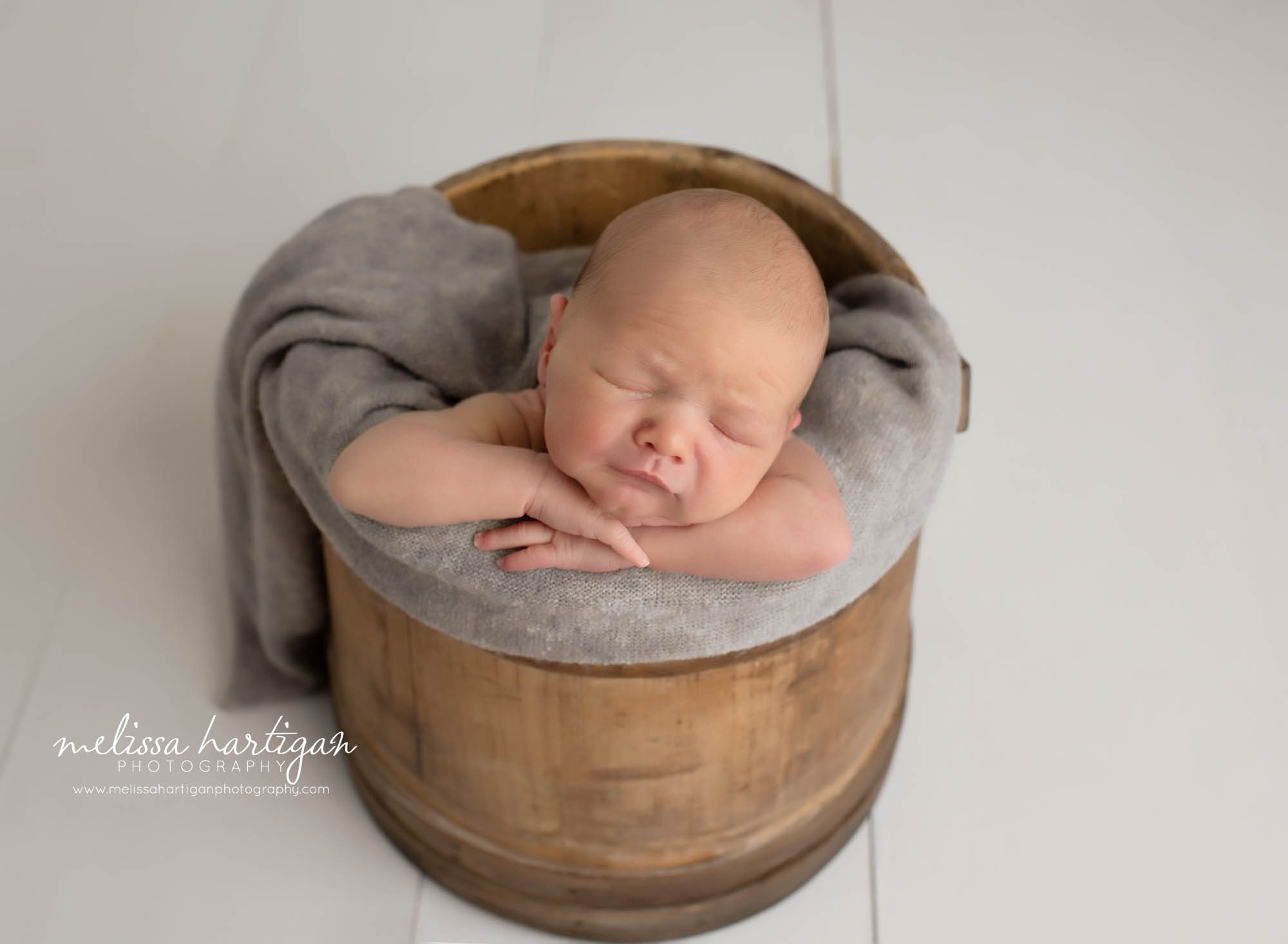 baby boy posed in wooden bucket prop with gray wrap