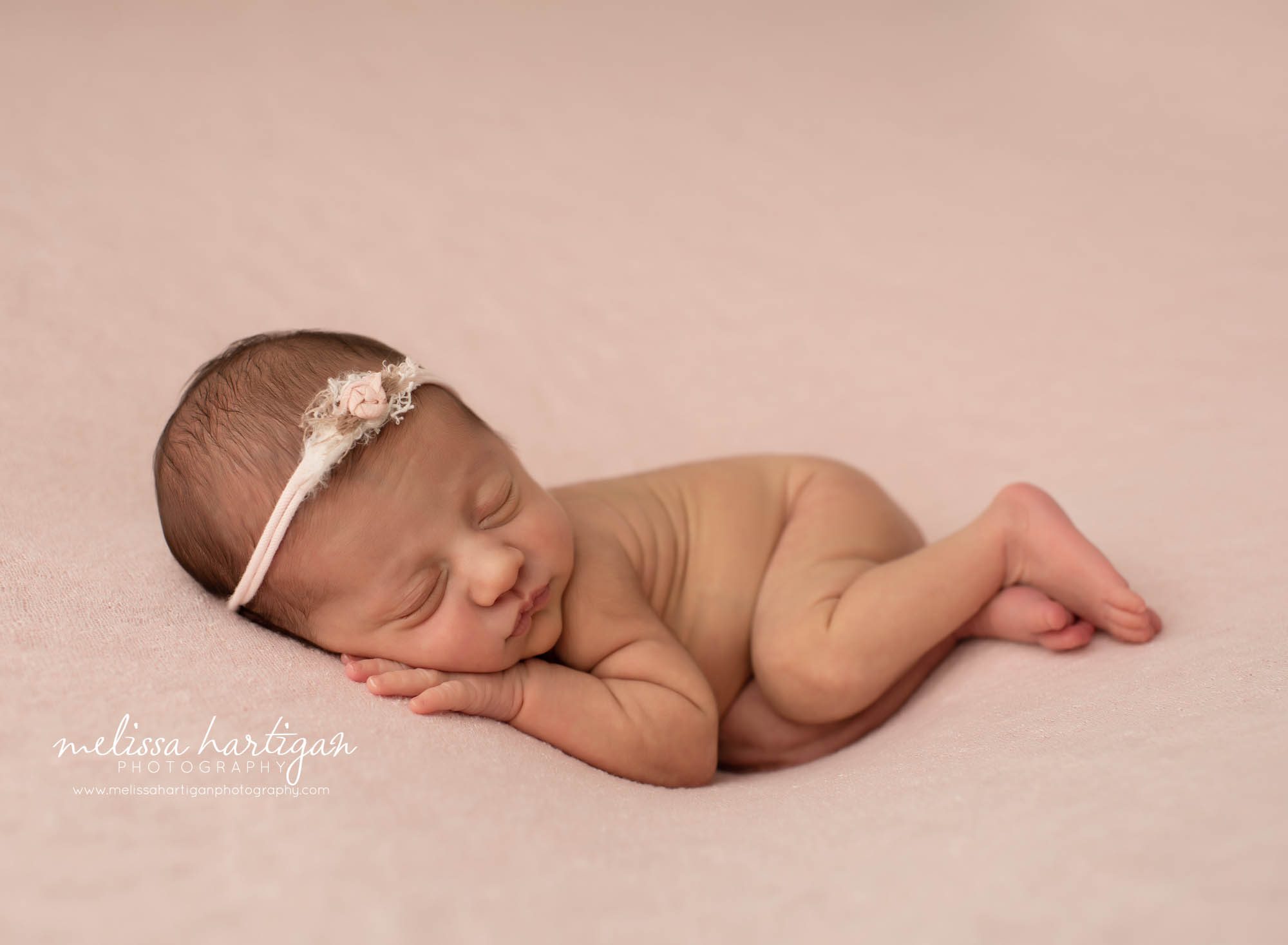 baby girl posed on pink backdrop with flower headband