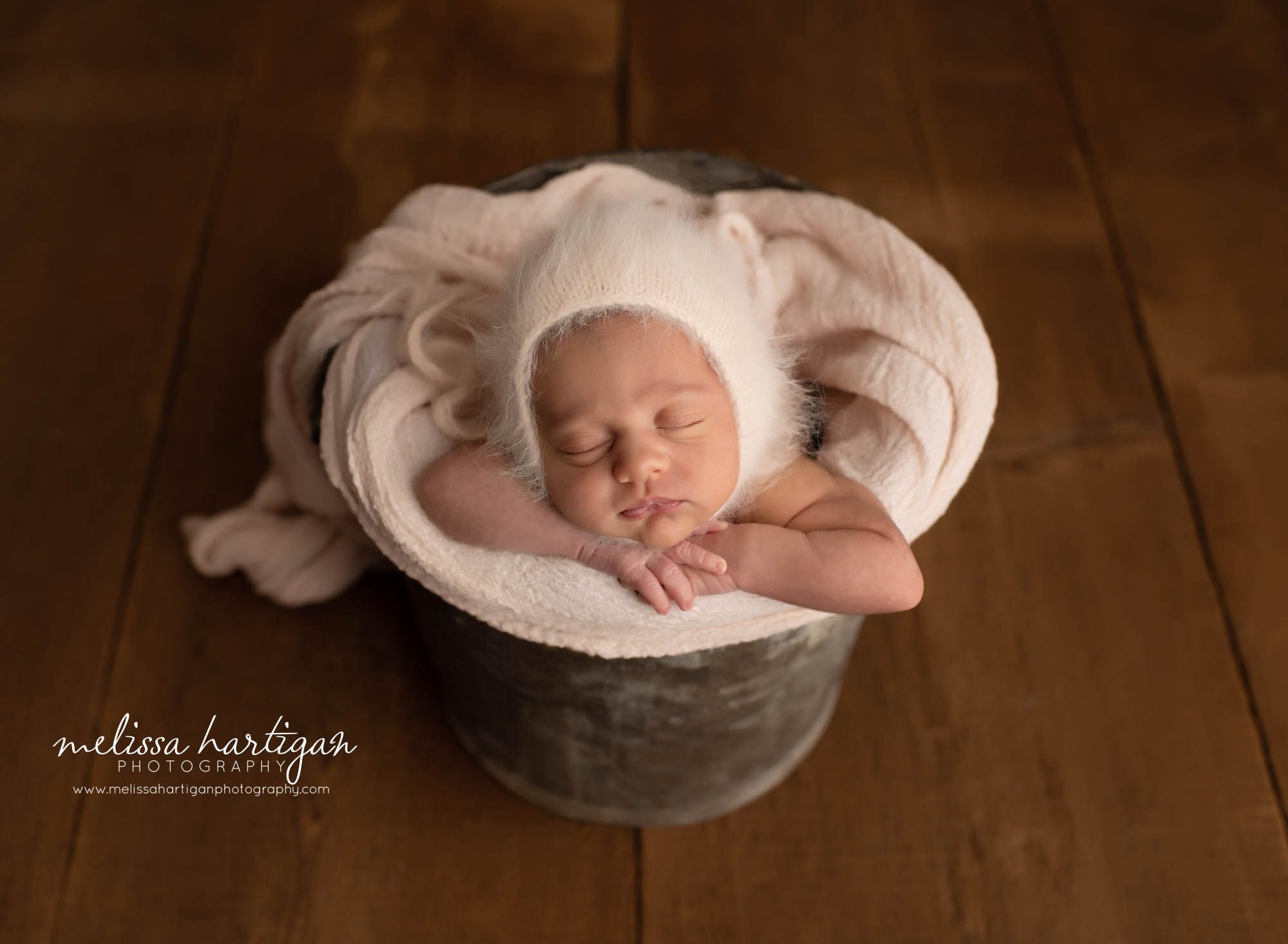 baby girl posed with angora knitted bonnet posed in bucket with chin on hands