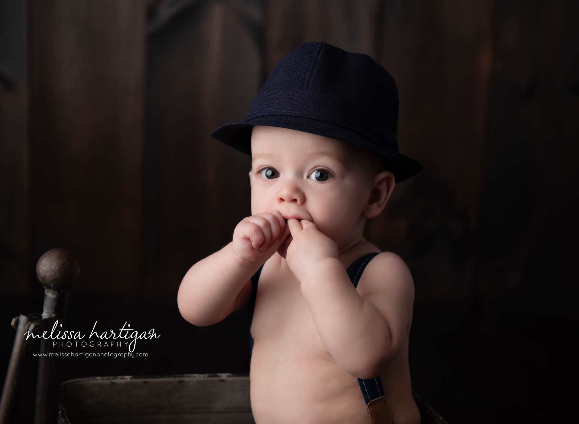 baby boy sitting in prop with fingers in mouth