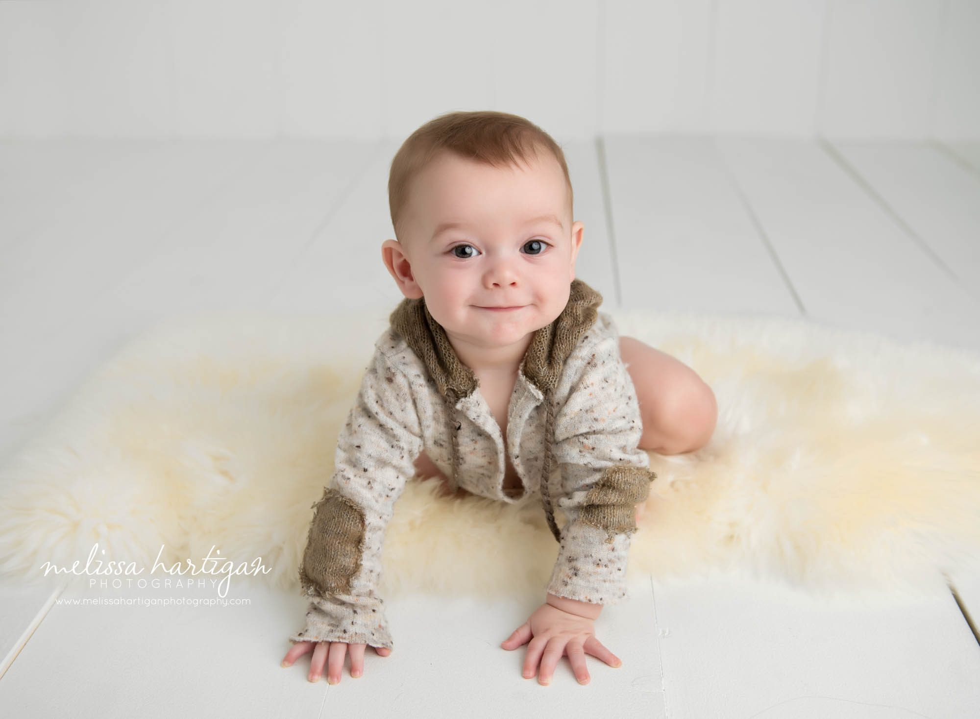 baby boy crawling on cream furry rug in studio photo session