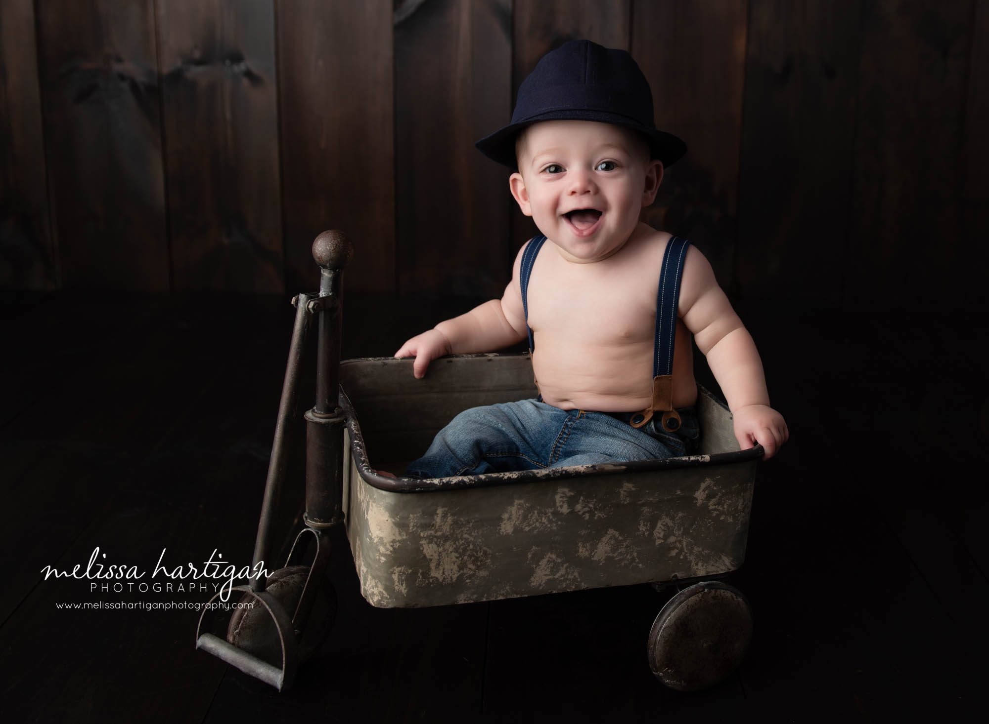 baby boy sitting in metal cart smiling at camera Tolland CT Baby Photographer