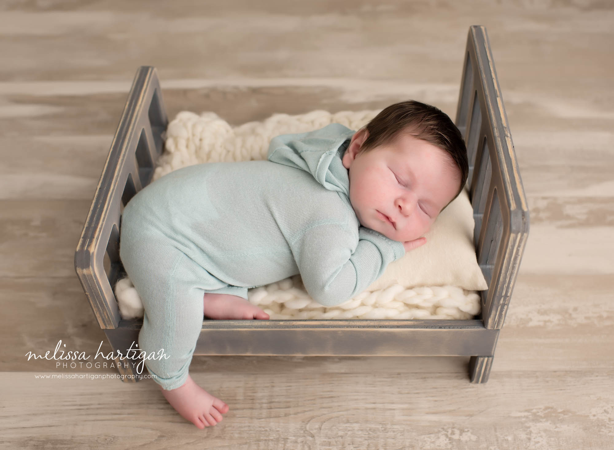 baby boy wearing light blue outfit posed on wooden bed