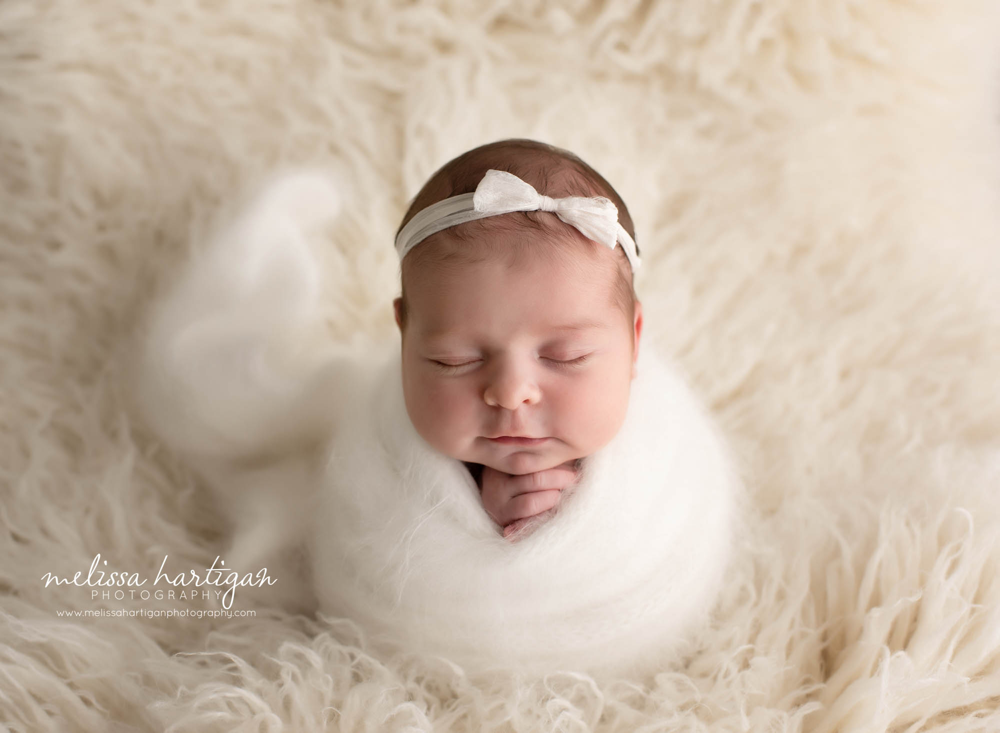 Newborn baby girl wrapped in white knitted wrap and white bow headband CT newborn photography session