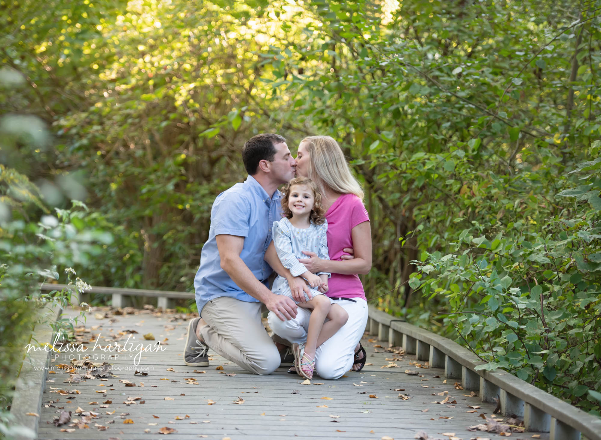 mom dad kissing behind daughter family photo CT Family Photographer