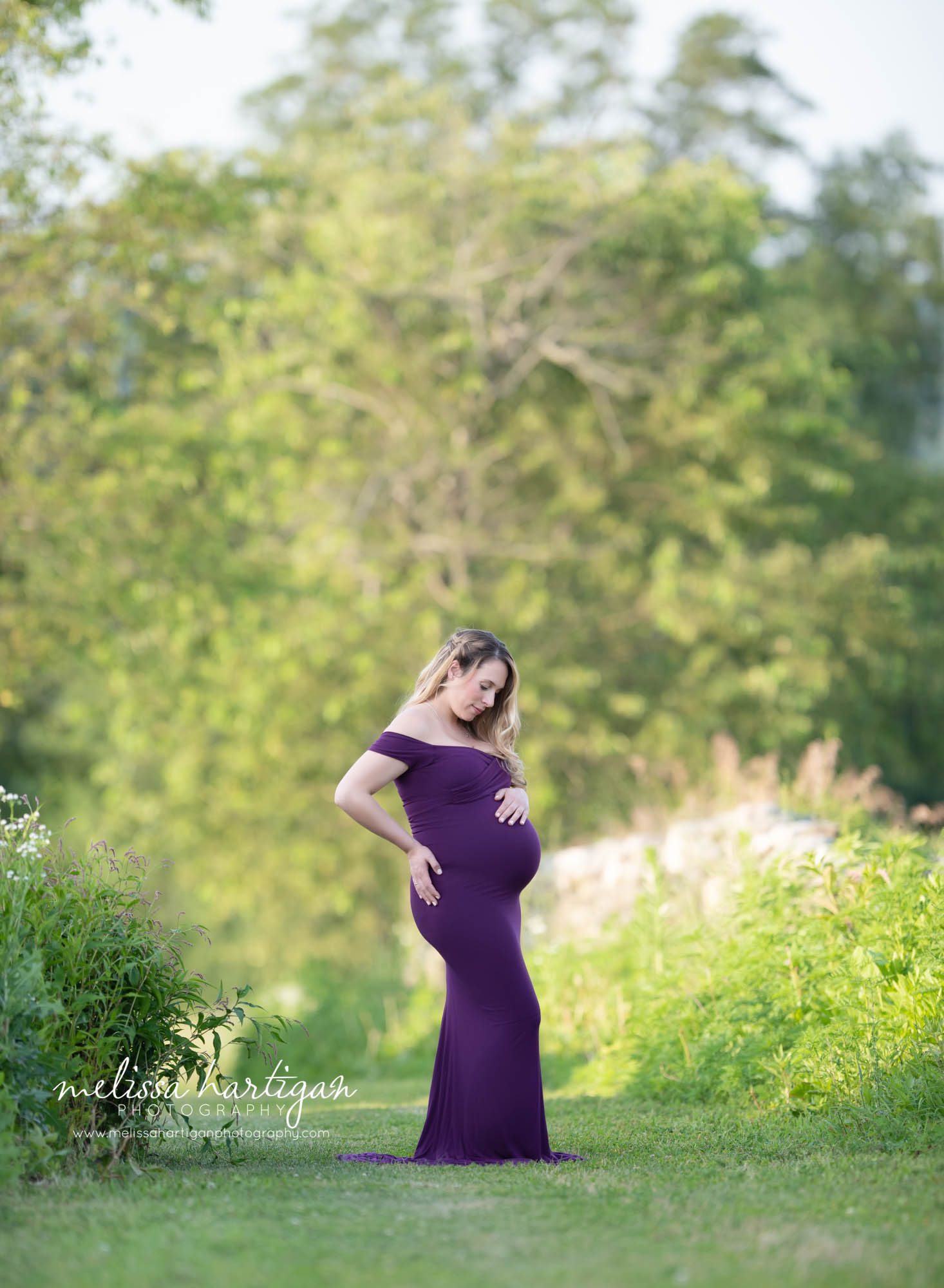 pregnant mom standing in field holding baby bump