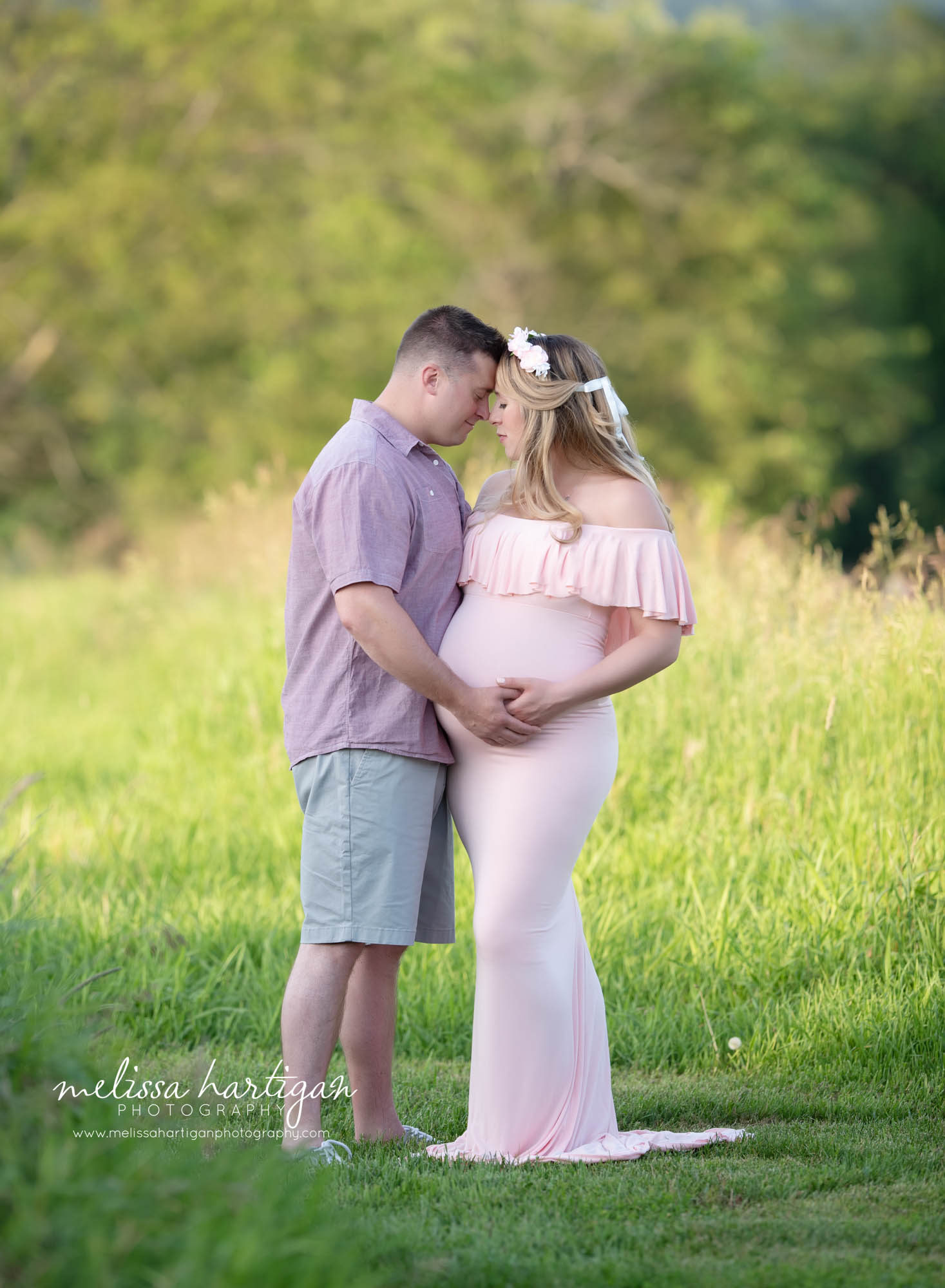 pregnant mom and dad to be standing in field holding baby bump touching foreheads together CT maternity Photographer