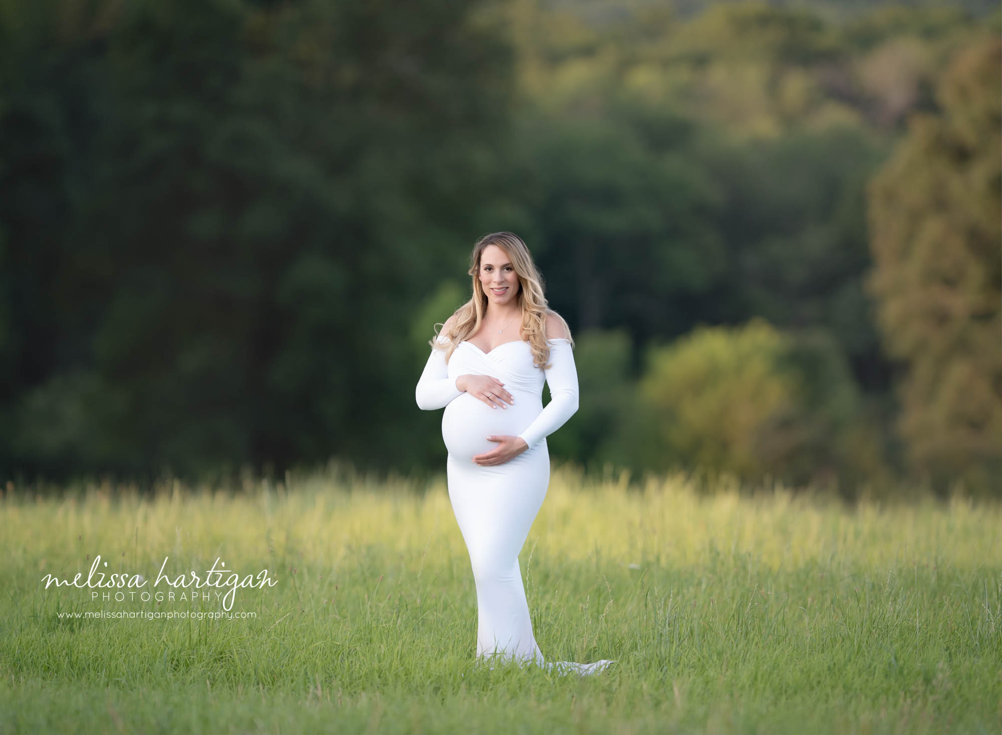 Pregnant mom standing in field wearing white form fitting maternity dress with sweetheart neckline maternity Photographer CT