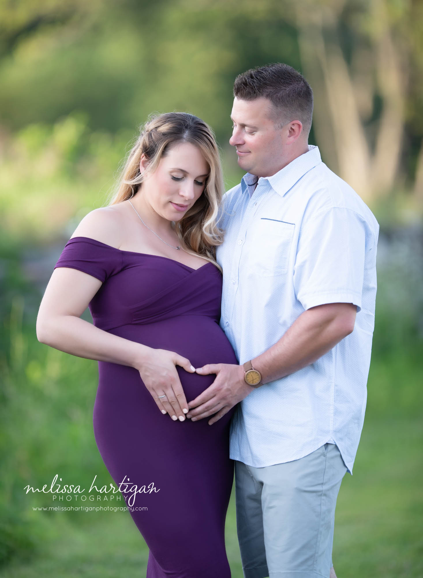 dad to be looking at mom to be holding baby bump with their hands in the shape of a heart CT pregnancy photos Maternity Session