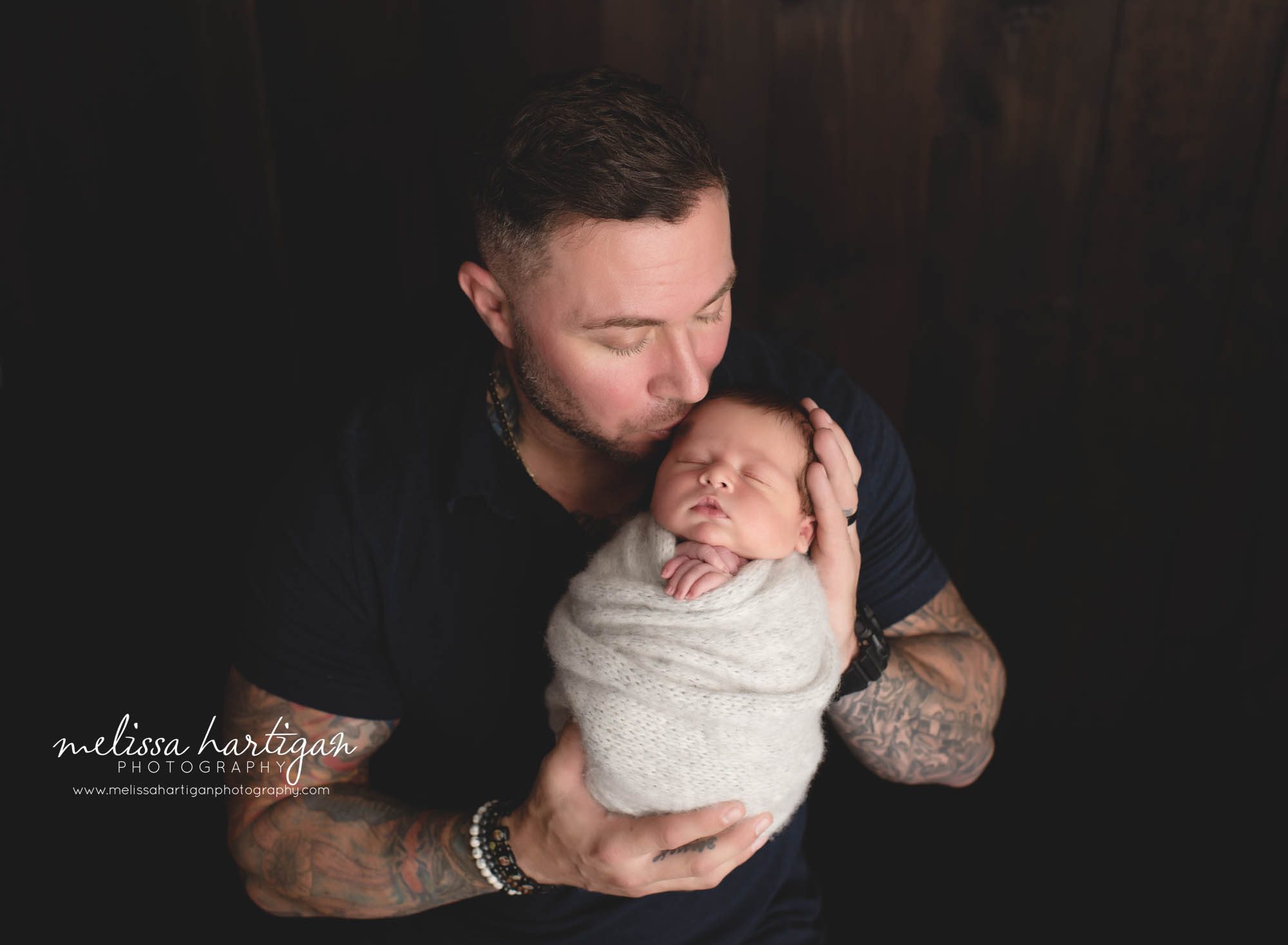 Dad holding newborn son in studio newborn photography session