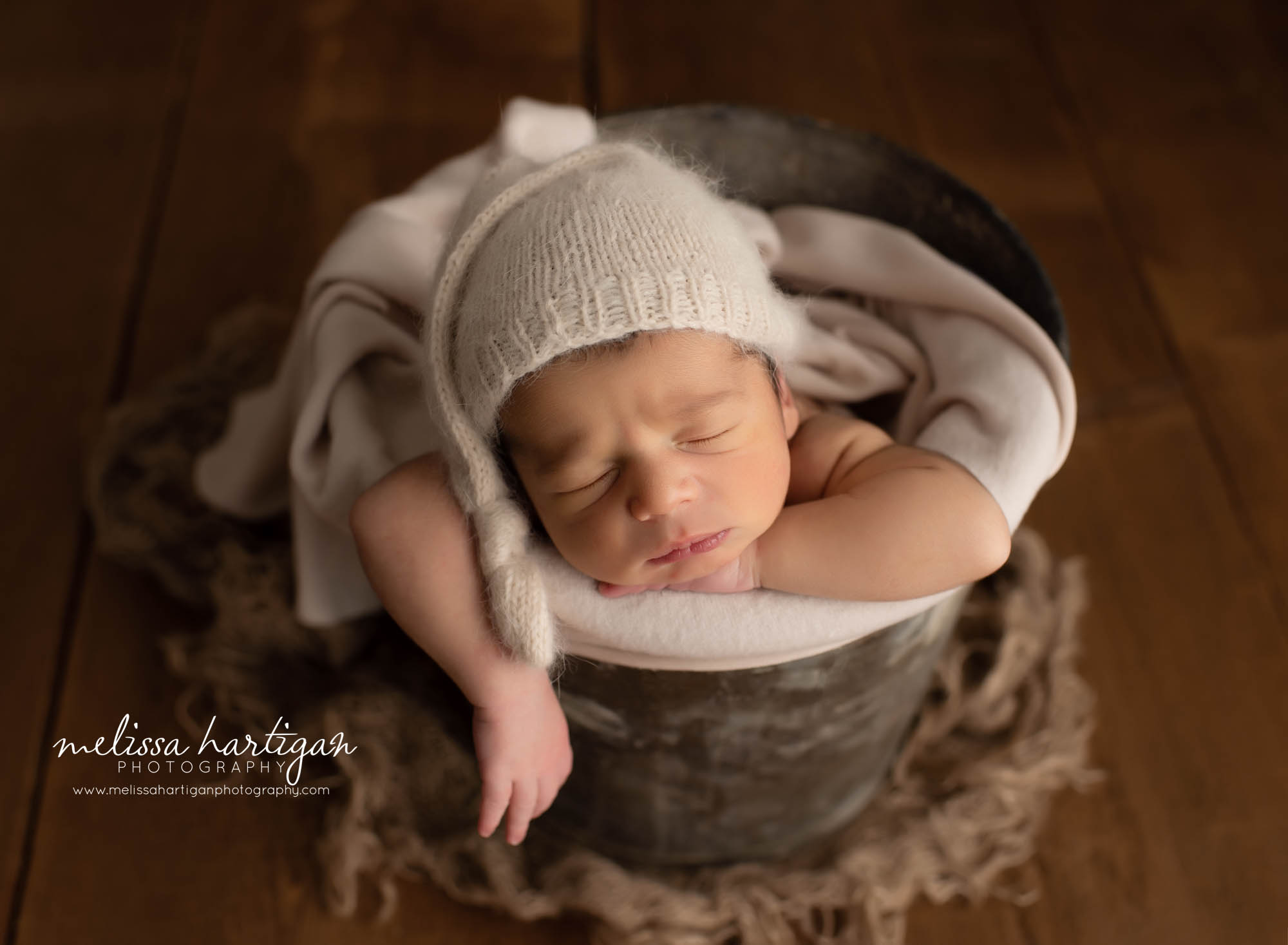 baby boy posed in bucket with knitted sleepy cap on CT newborn Photography