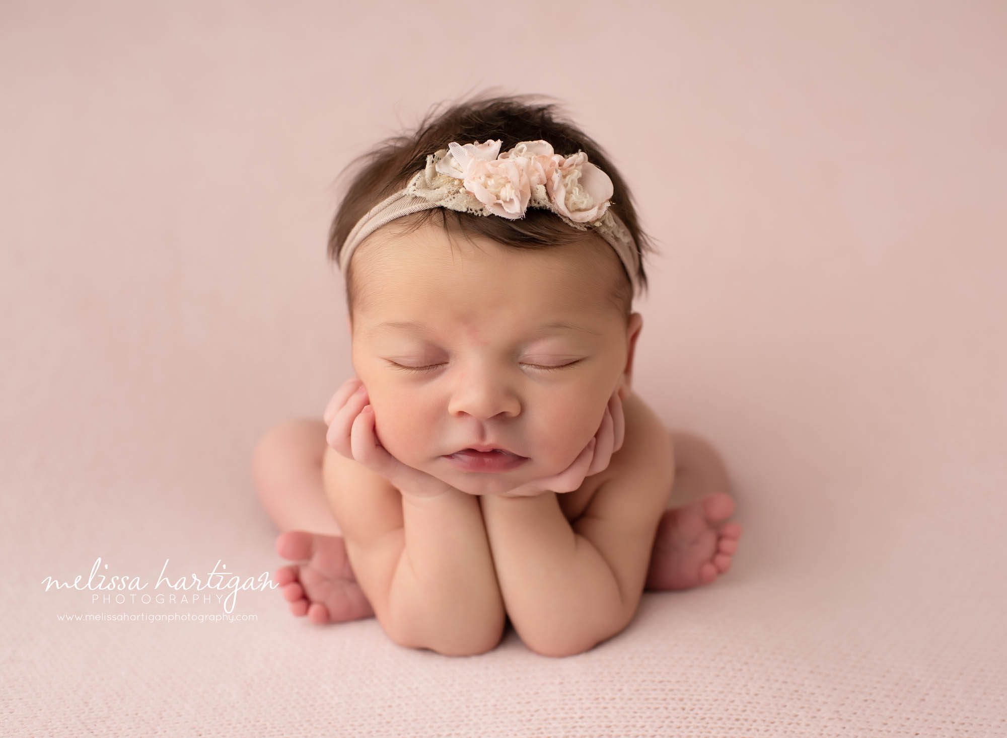 Baby girl posed froggy pose on pink backdrop with pink headband