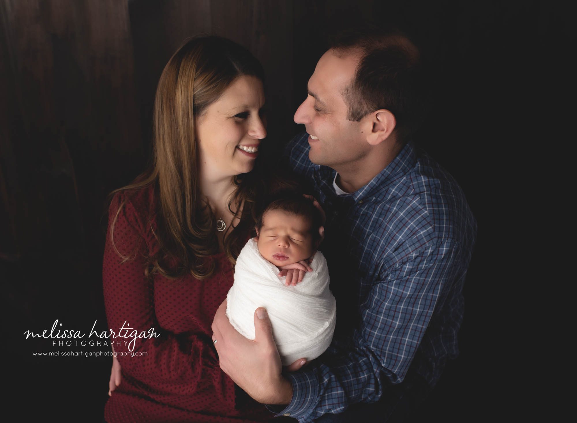 mom and dad holding newborn son wrapped newborn session