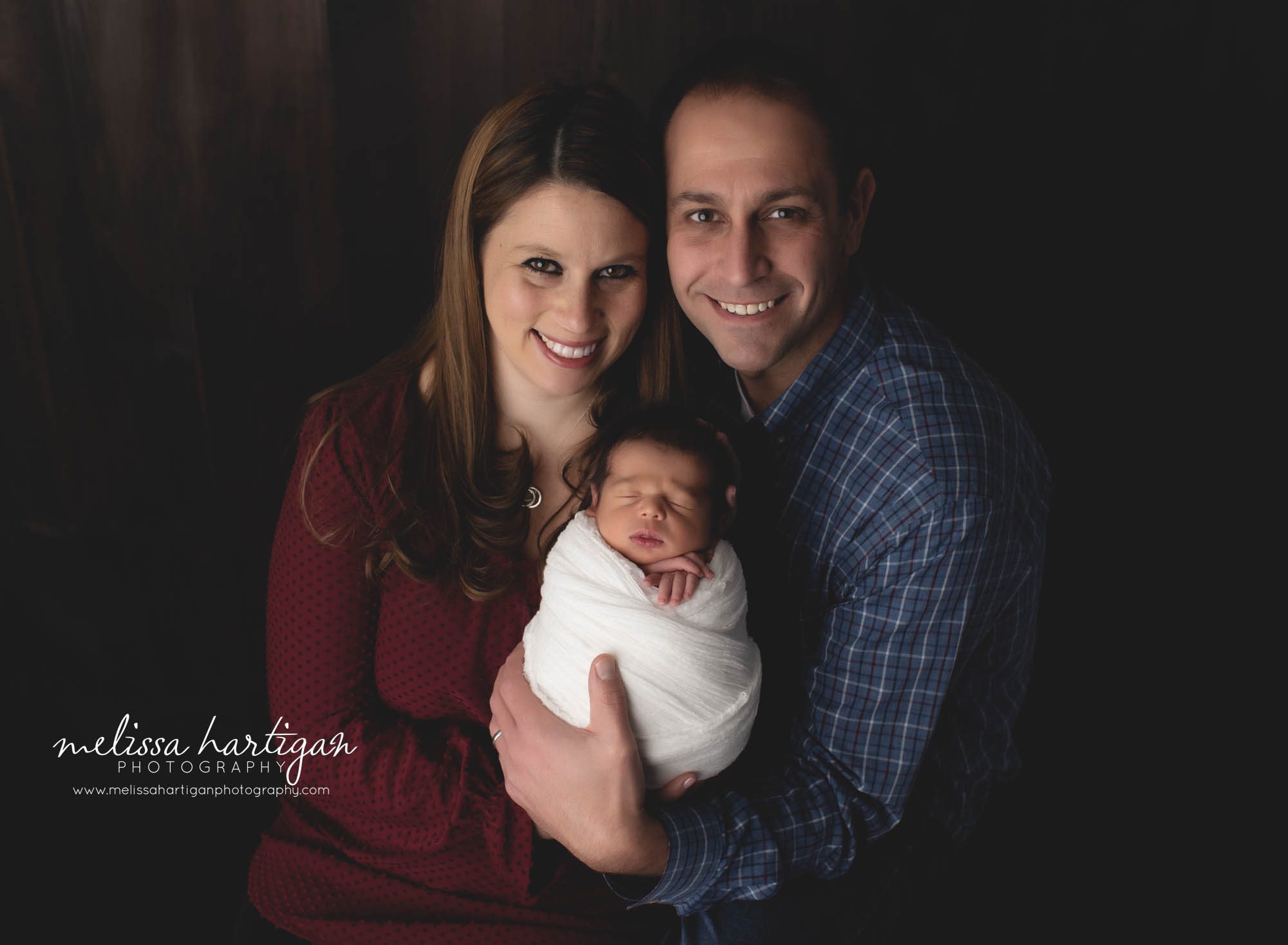 mom and dad holding newborn son wrapped newborn session in studio