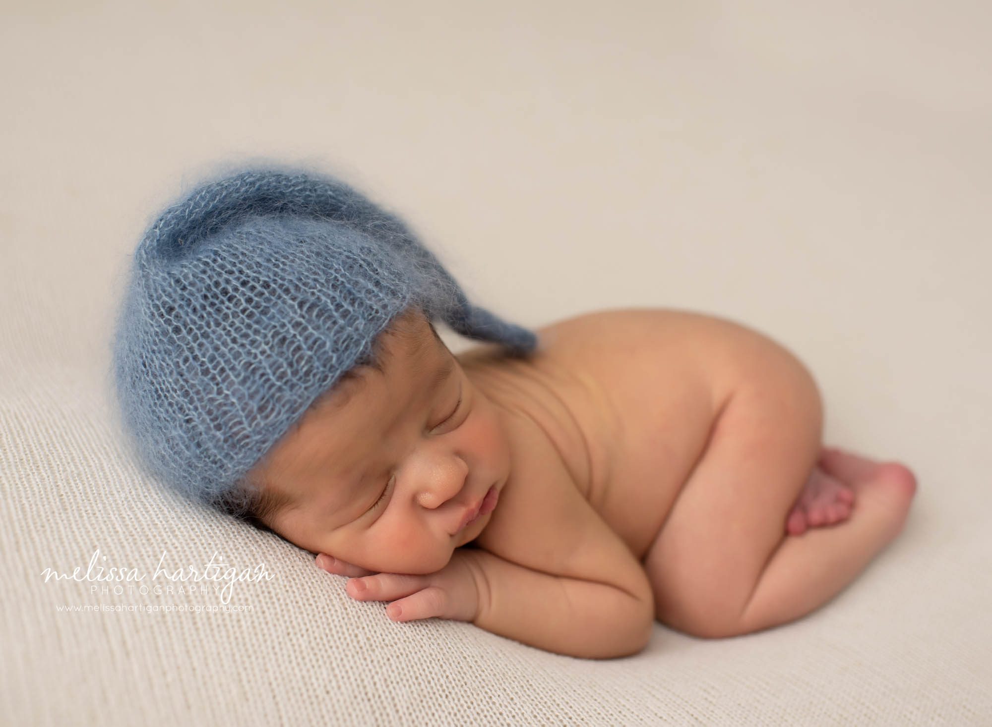 baby boy posed with blue sleepy cap