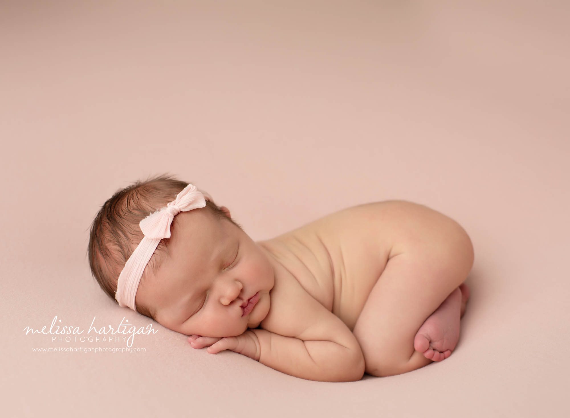 newborn baby girl posed on tummy with bum up wearing pink bow headband in studio newborn photography session Tolland CT Newborn Photography