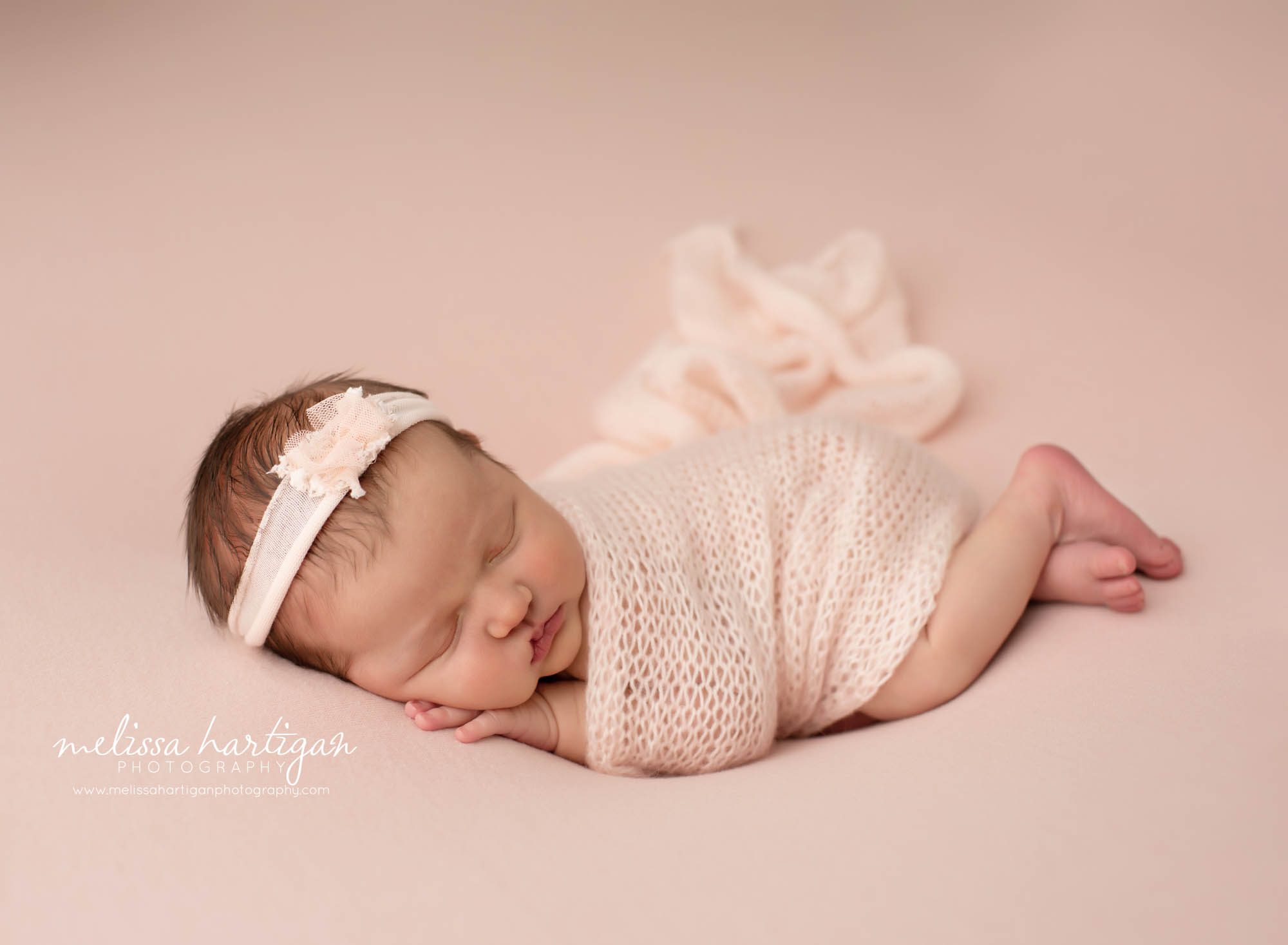 newborn baby girl sleeping posed side with blush pink headband on and blush pink knitted wrap Tolland CT Newborn Photographer