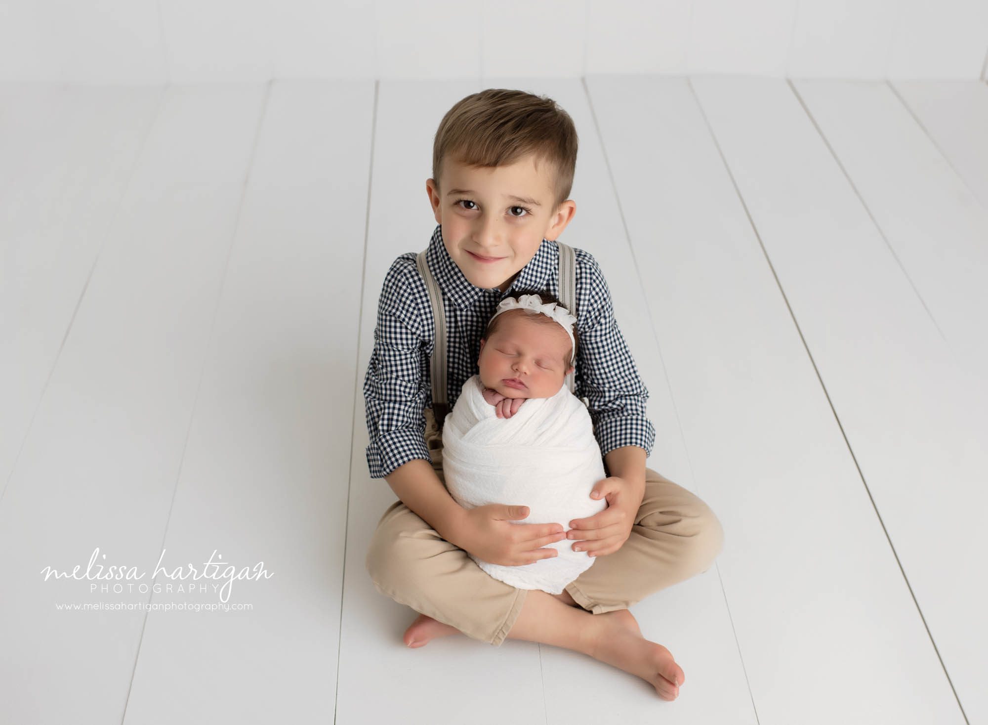 Newborn baby girl wrapped in big brothers arms for sibling pose newborn photography session CT