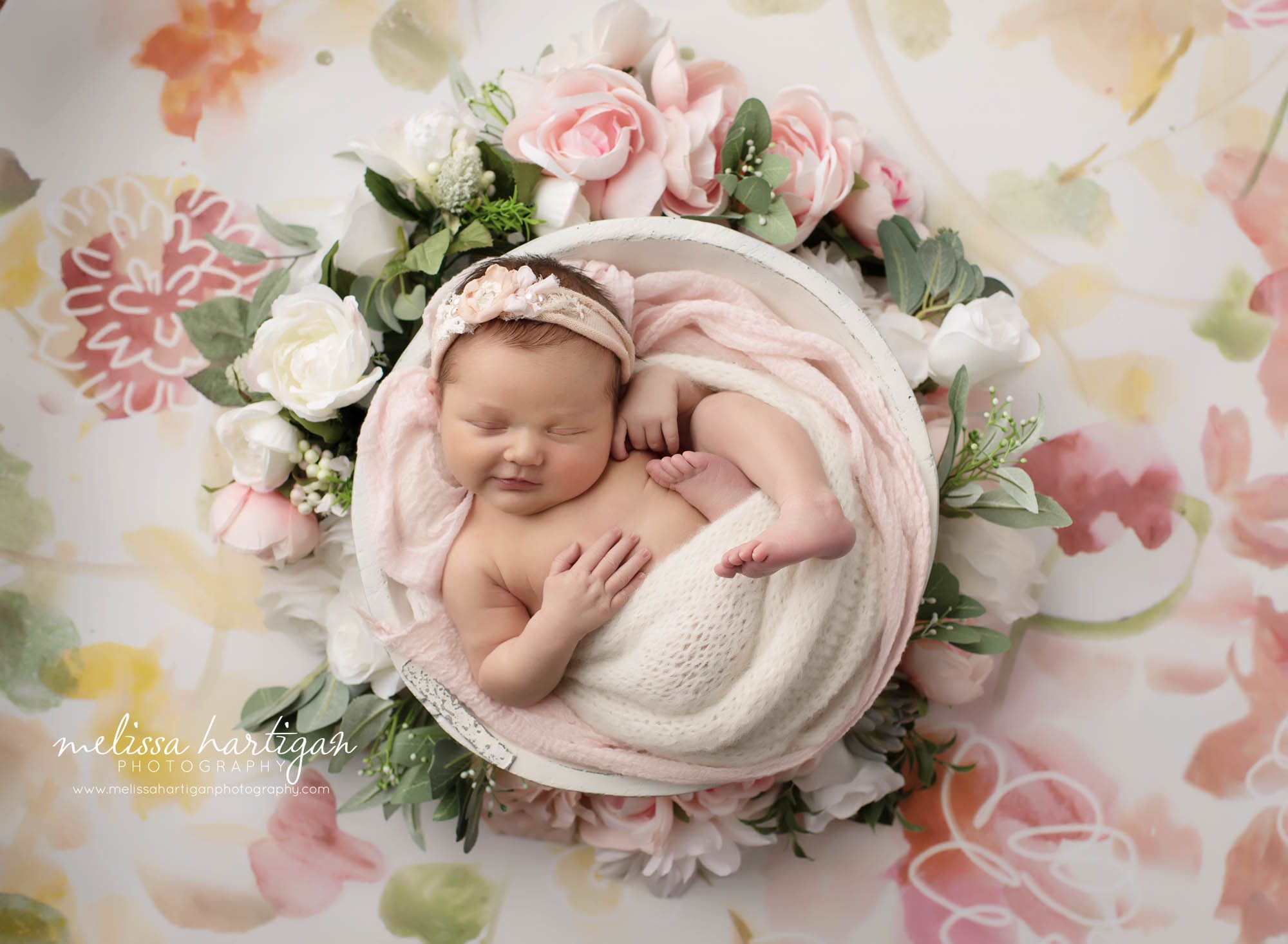 Baby girl posed in white wooden prop with pink florals around wooden bowl