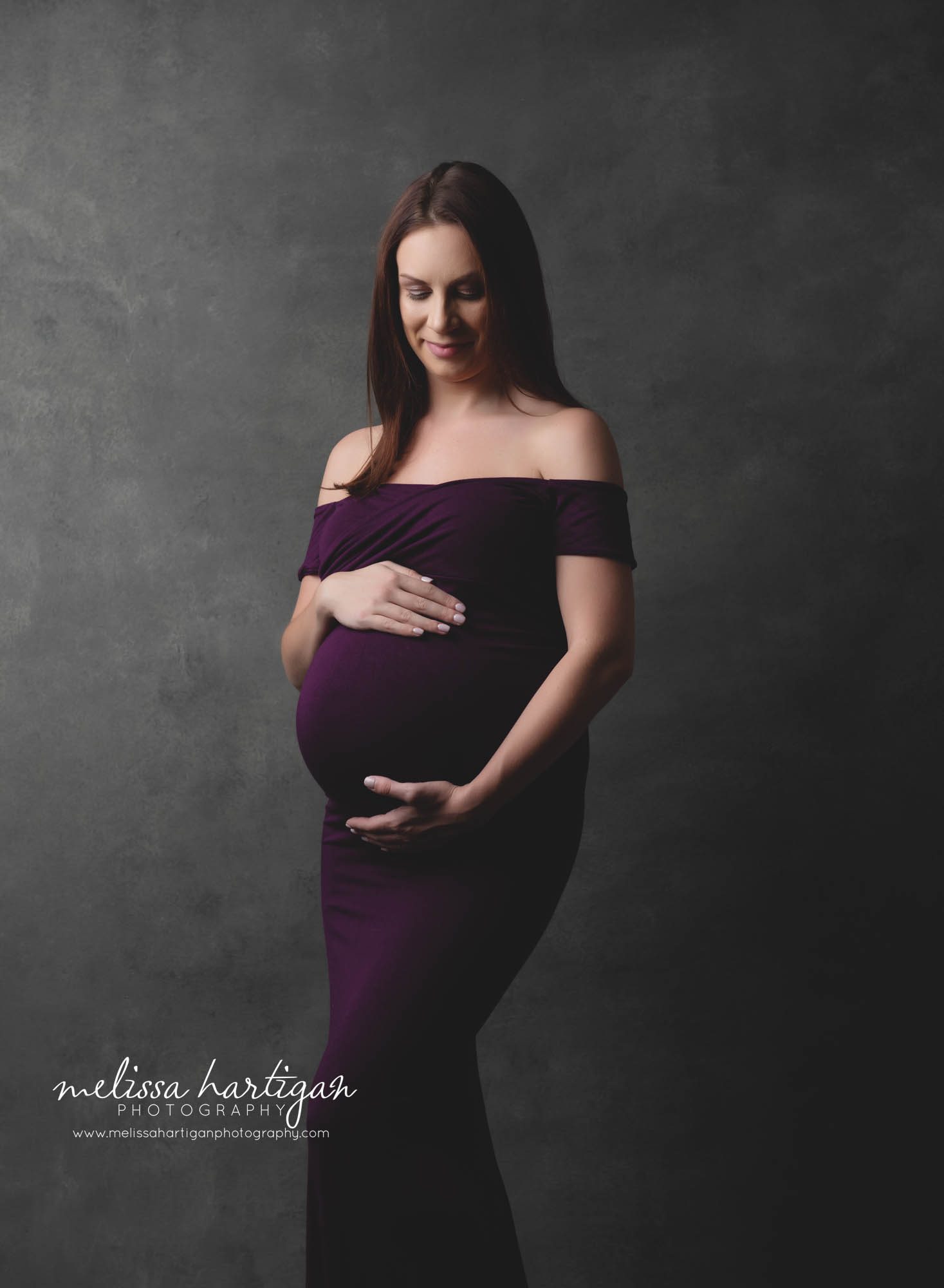 Pregnant mom wearing long purple dress studio maternity pictures