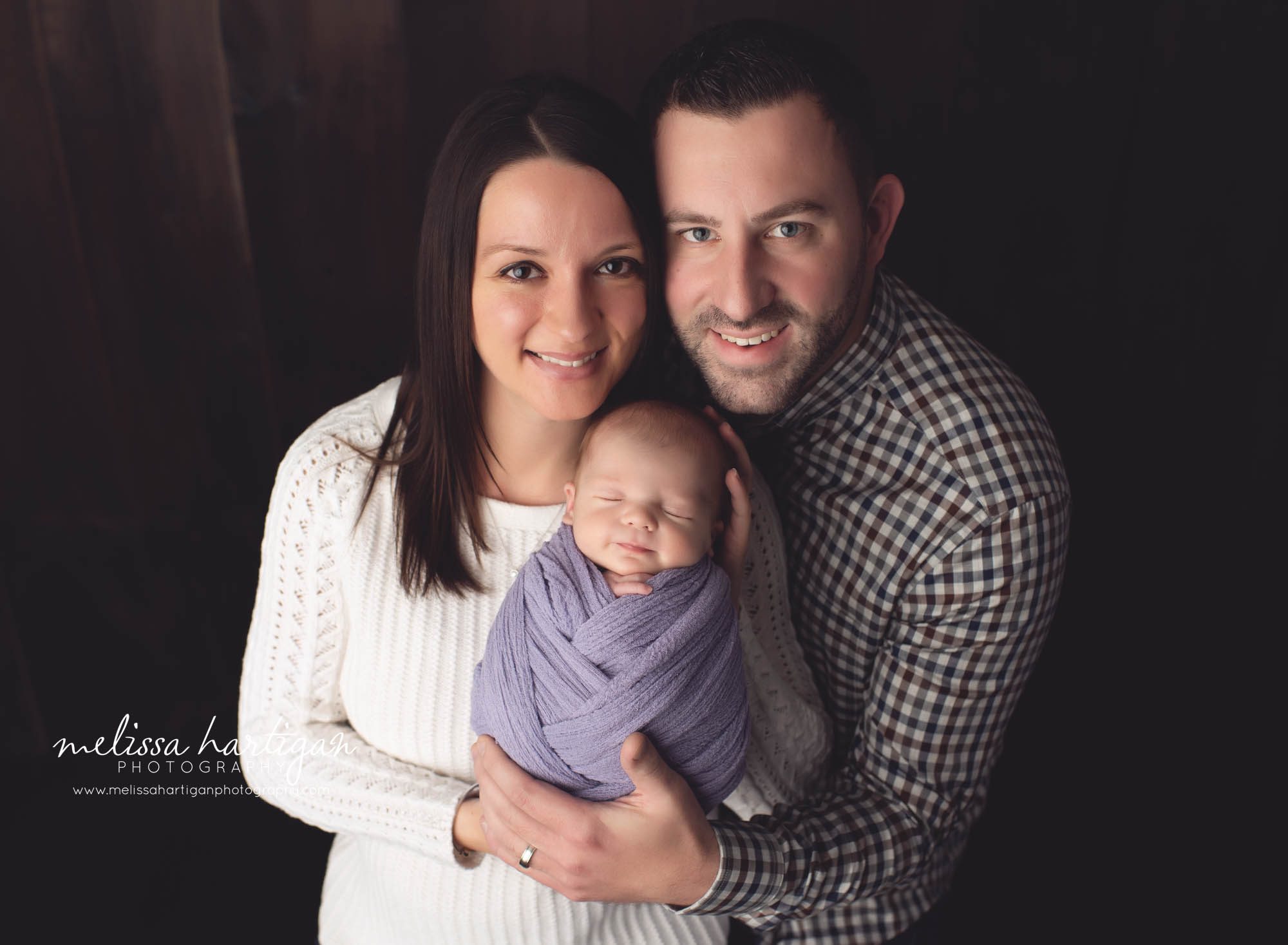 mom and dad holding newborn baby girl together in studio newborn photography session