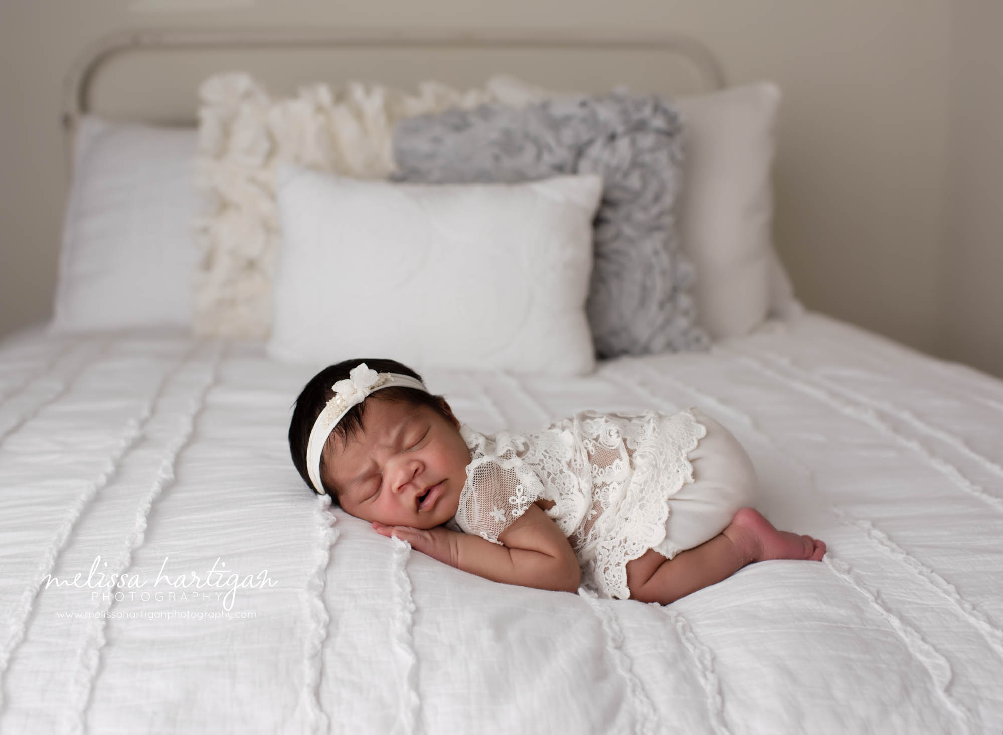 baby girl posed on bed wearing clace cream outfit and headband