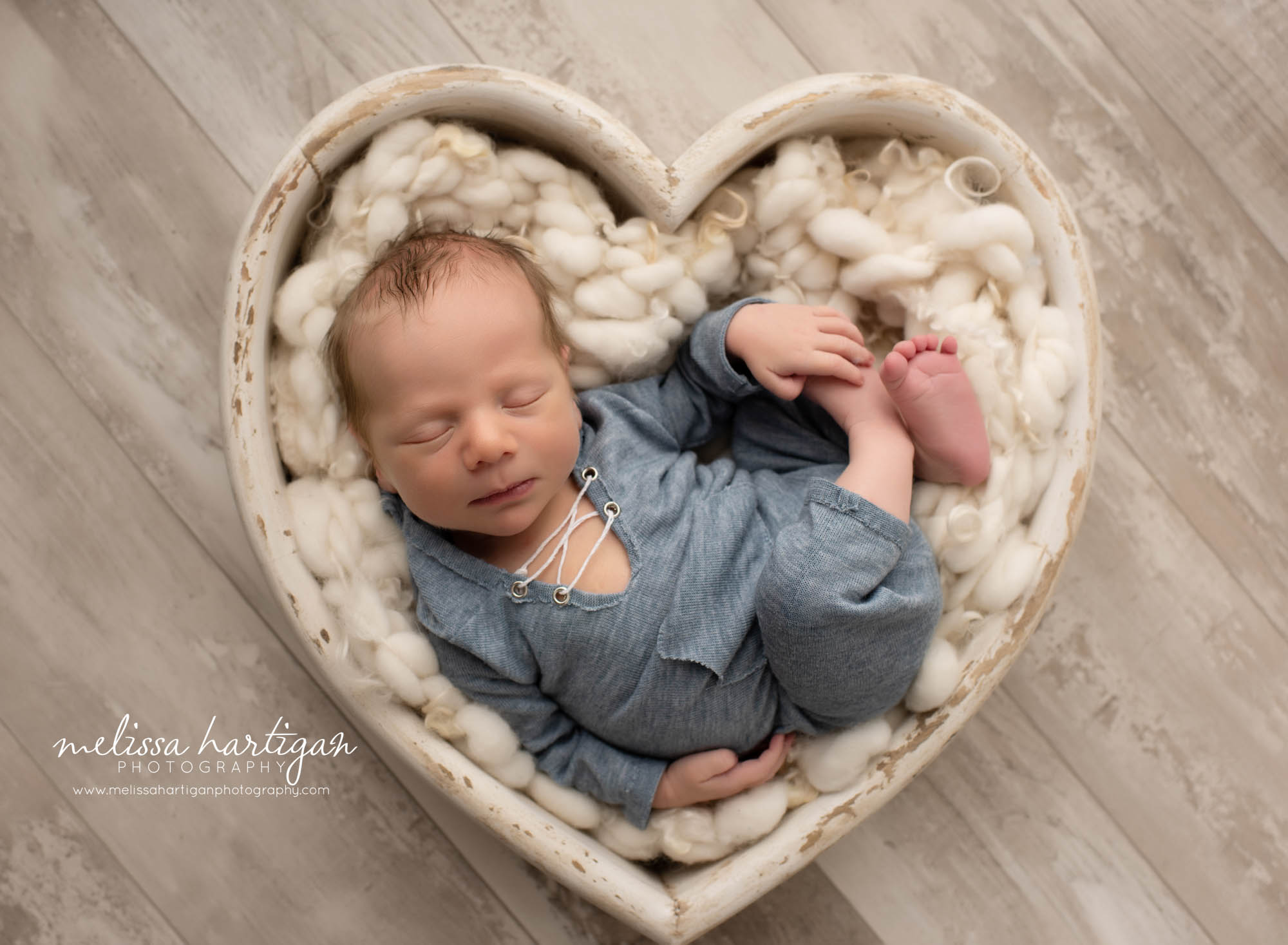 baby boy posed in wooden heart prop wearing blue outfit
