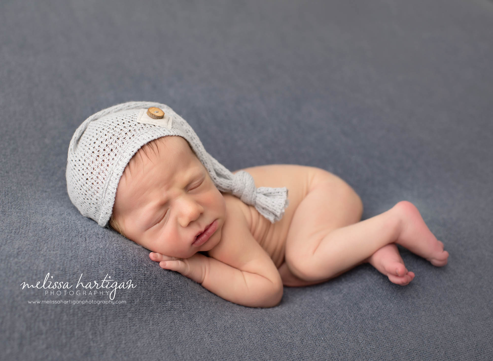 baby boy posed on side with sleepy cap newborn photography pictures