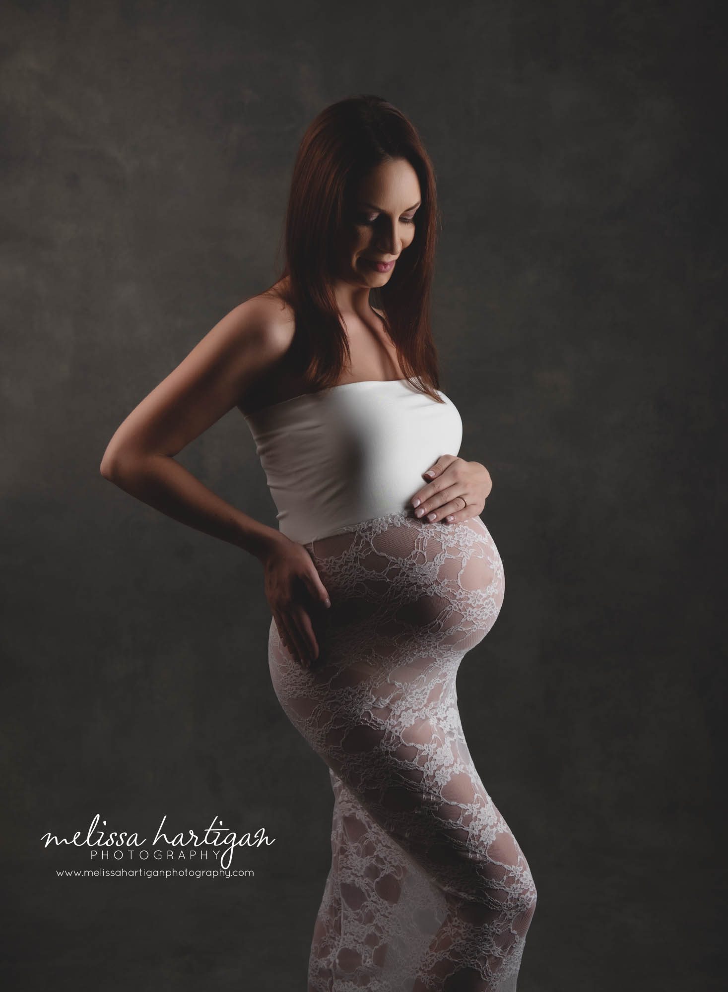 expectant mom wearing cream and lace maternity dress in studio