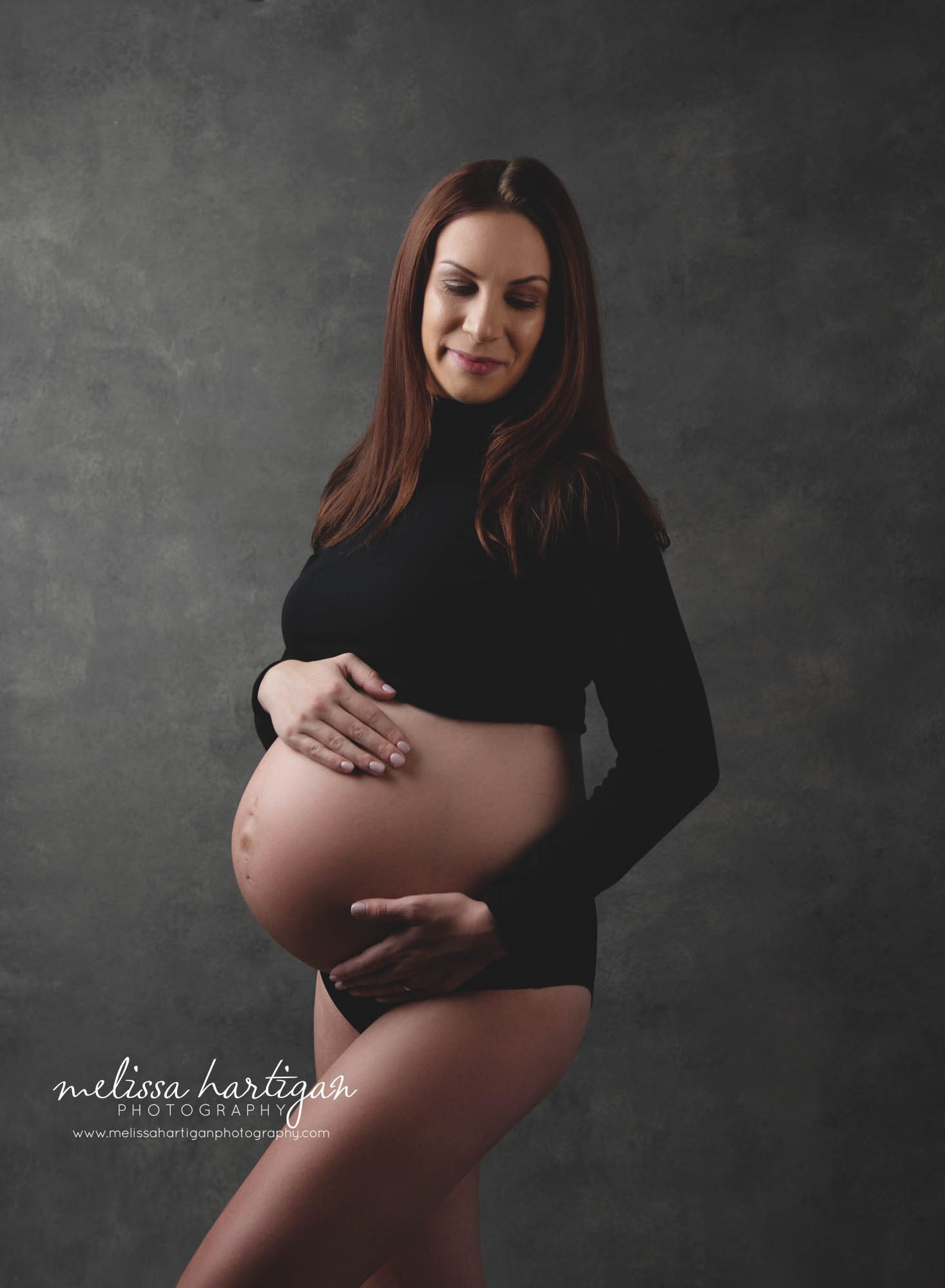 Pregnant mom wearing black long sleeved crop top in studio maternity photography pictures