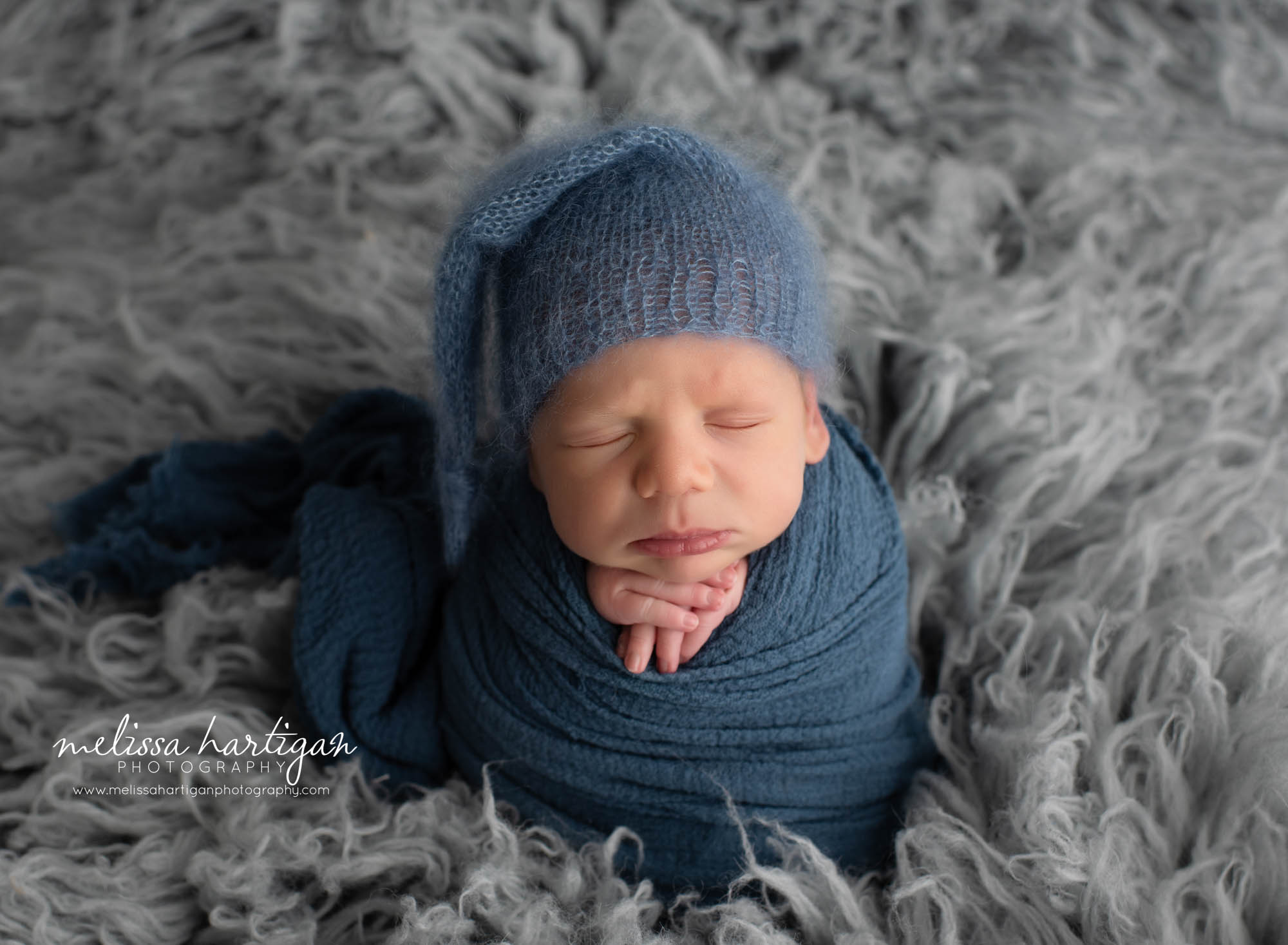 Baby boy wrapped inblue wrap wearing knitted sleepy cap