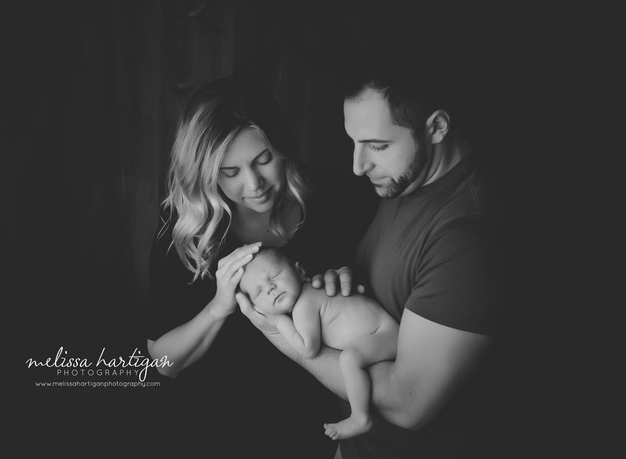 dad holding newborn son on arm mom softly touching her newborn son family photo newborn photography session Connecticut CT Photographer
