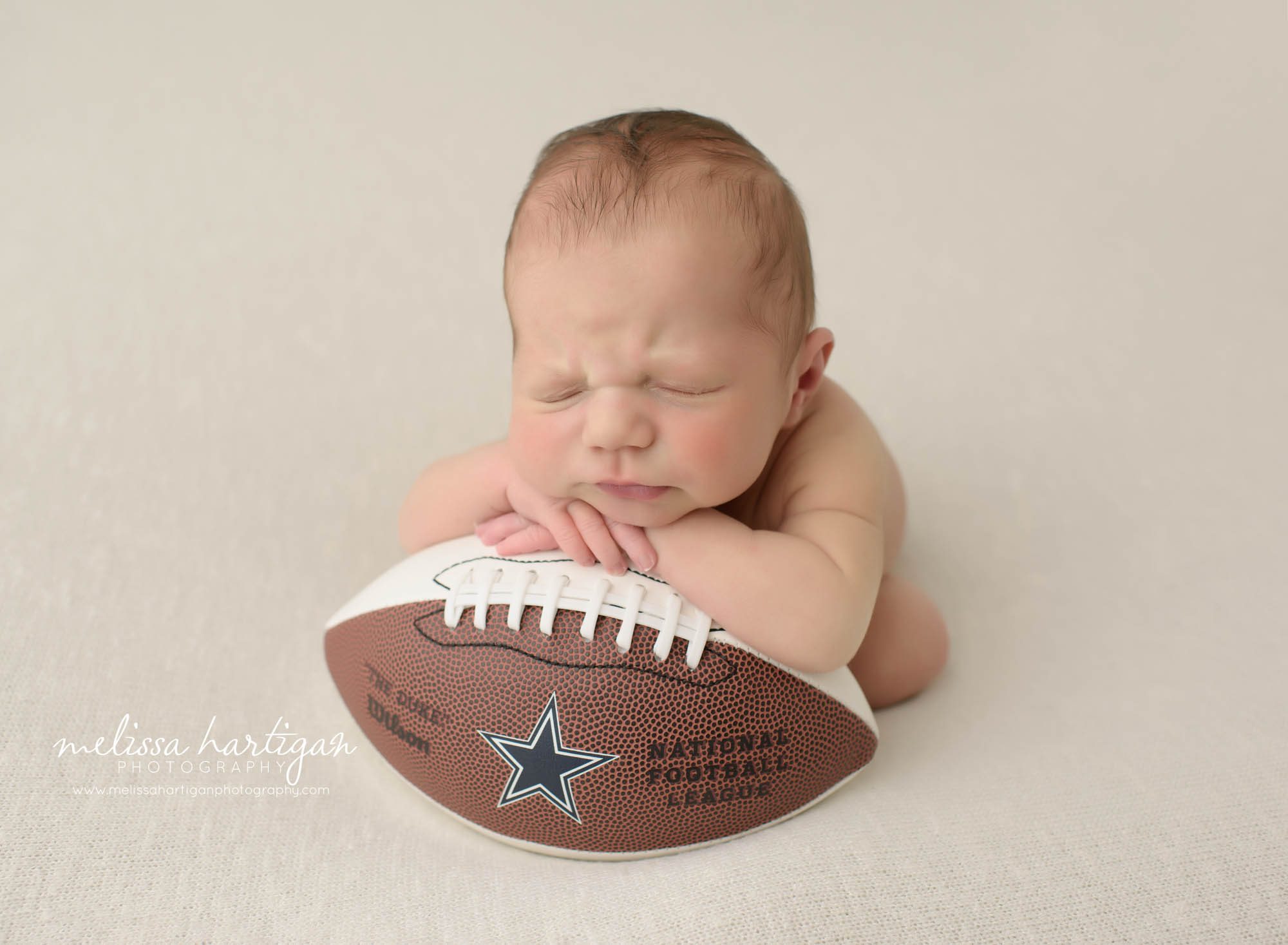 baby boy posed on Dallas Cowboys mini football in newborn photography pictures