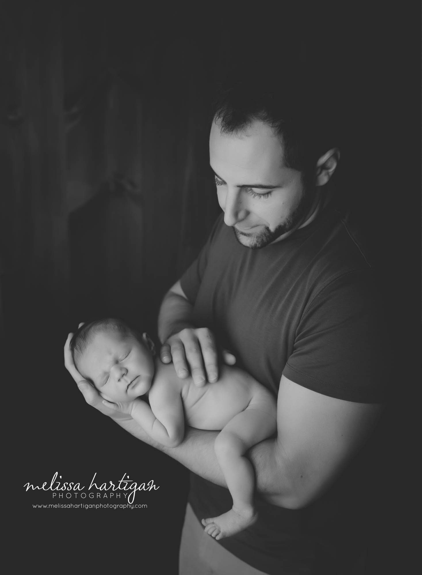dad holding newborn son on arm in parent photo newborn baby photography session CT photographer