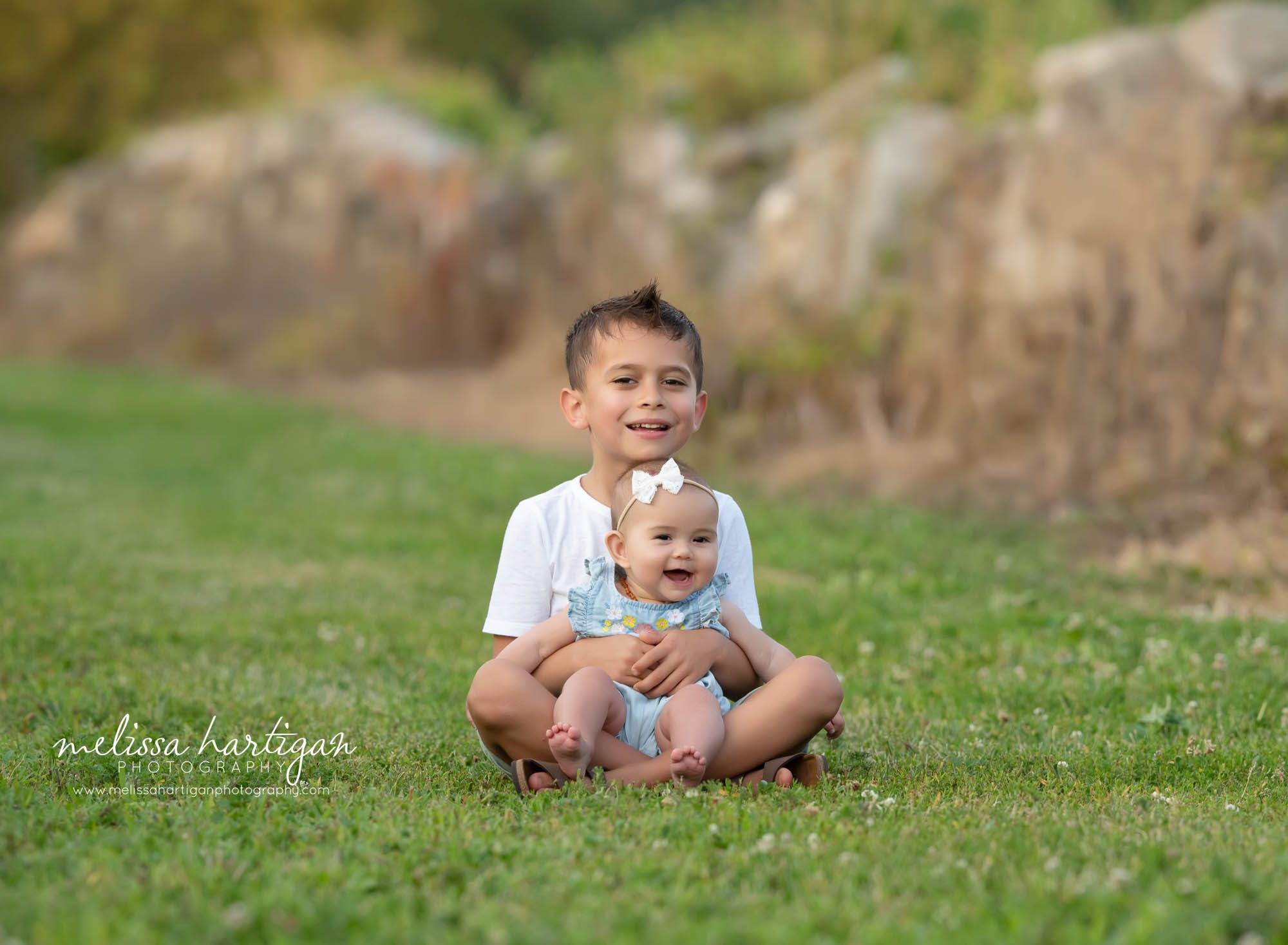 older brother sitting on grass with baby sister family photography session CT photographer