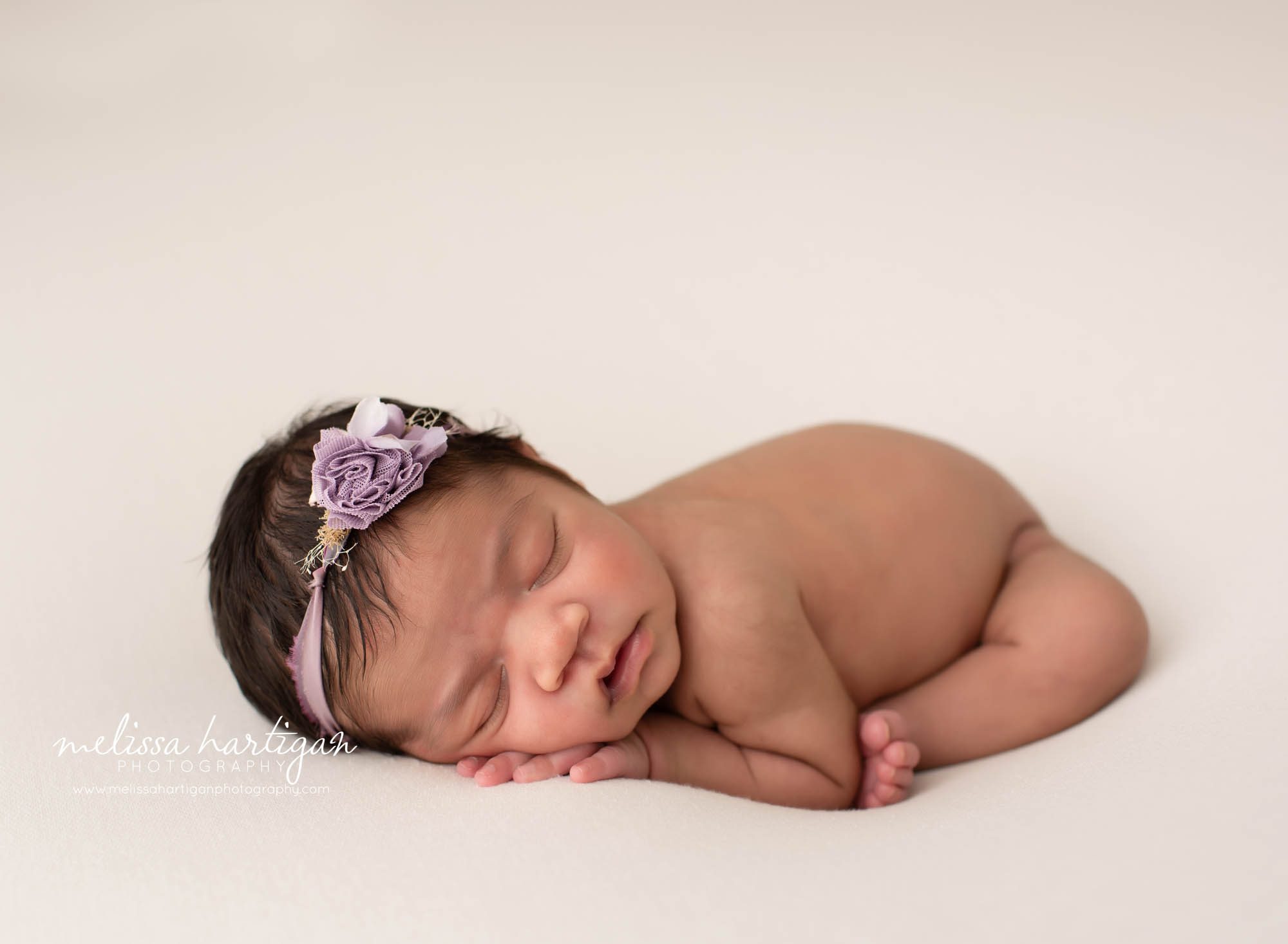 baby girl posed on cream backdrop with purple headband CT newborn Photography