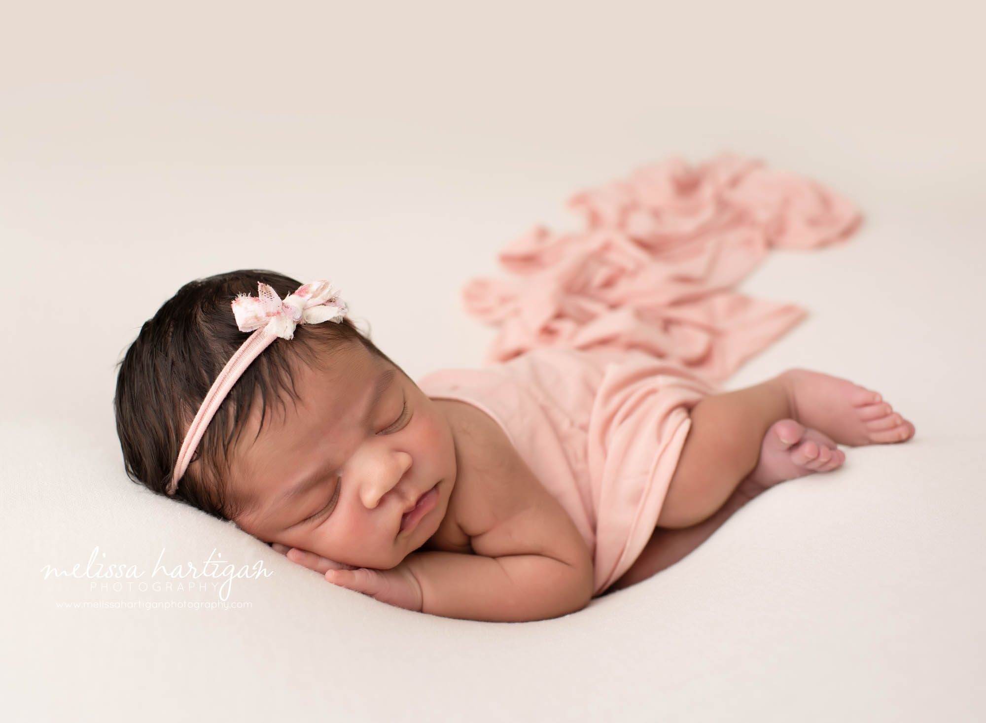 baby girl posed on cream backdrop with pink wrap and pink headband