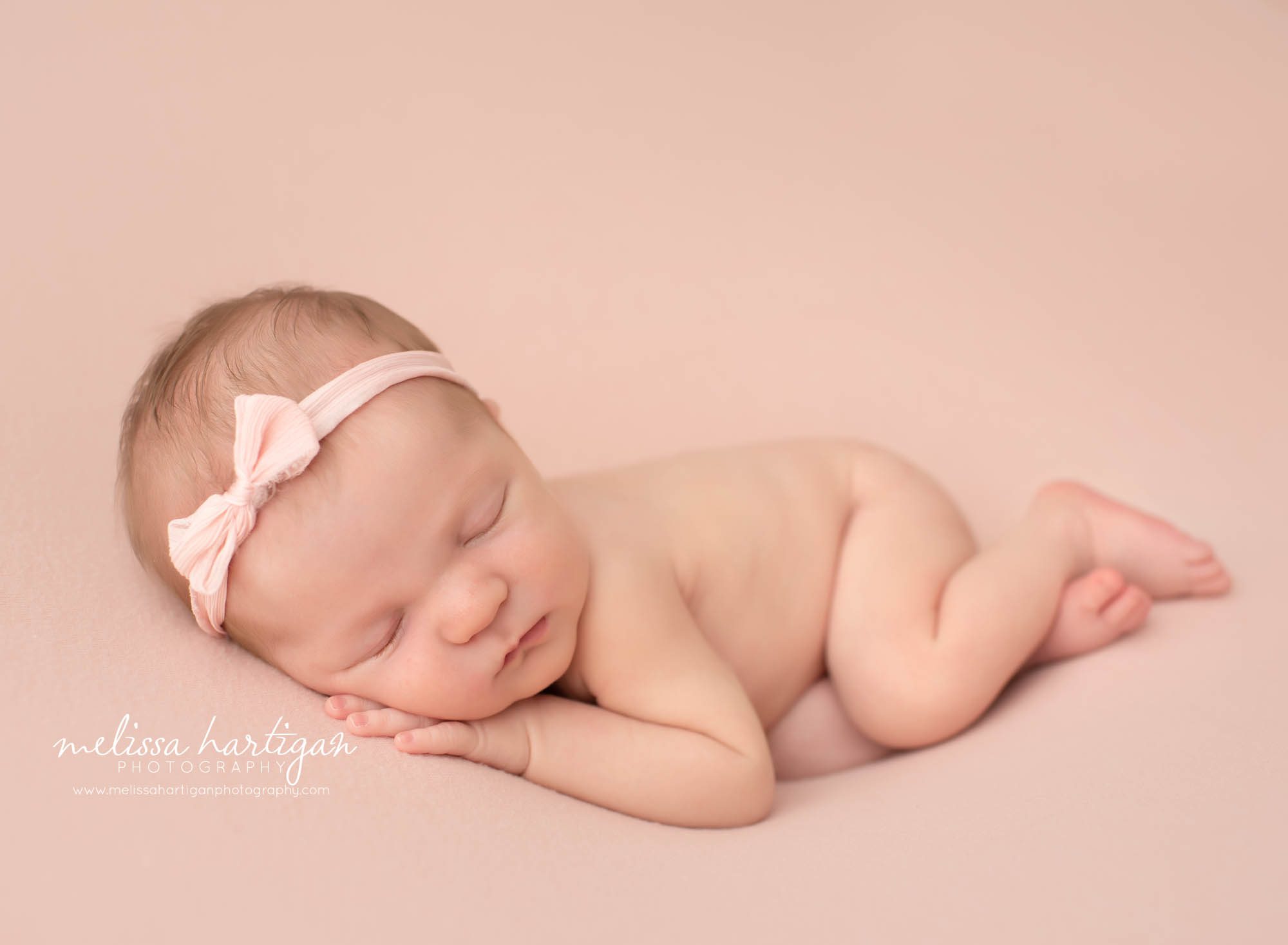 Baby girl posed on side with pink bow headband Connecticut newborn photographer