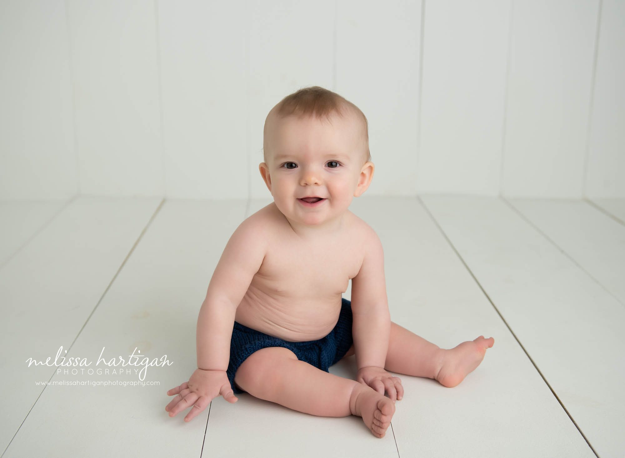 baby boy sitting on wooden boards smiling baby milestone photography Andover CT