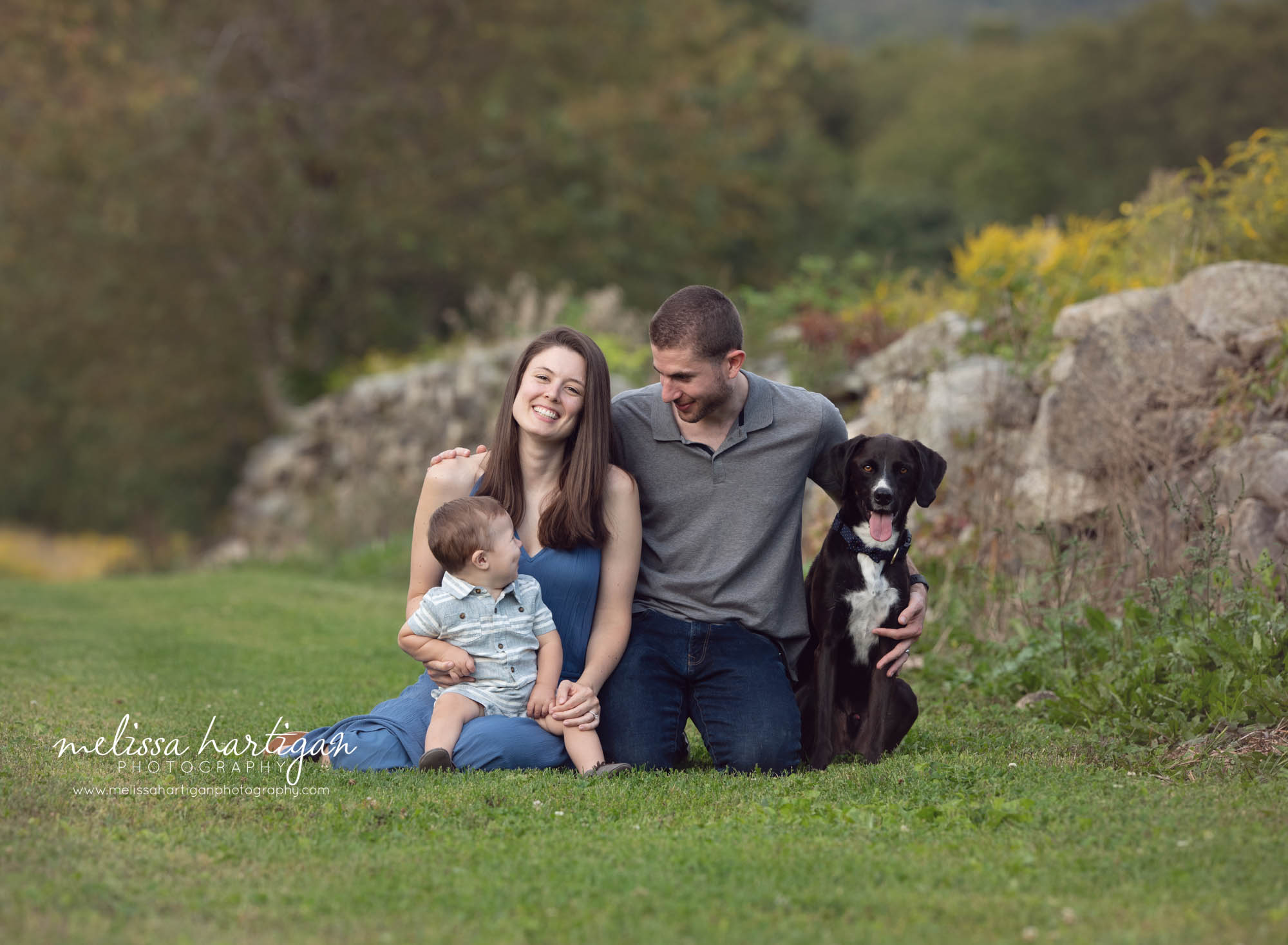 mom dad and family dog making toddler son smile family photo session