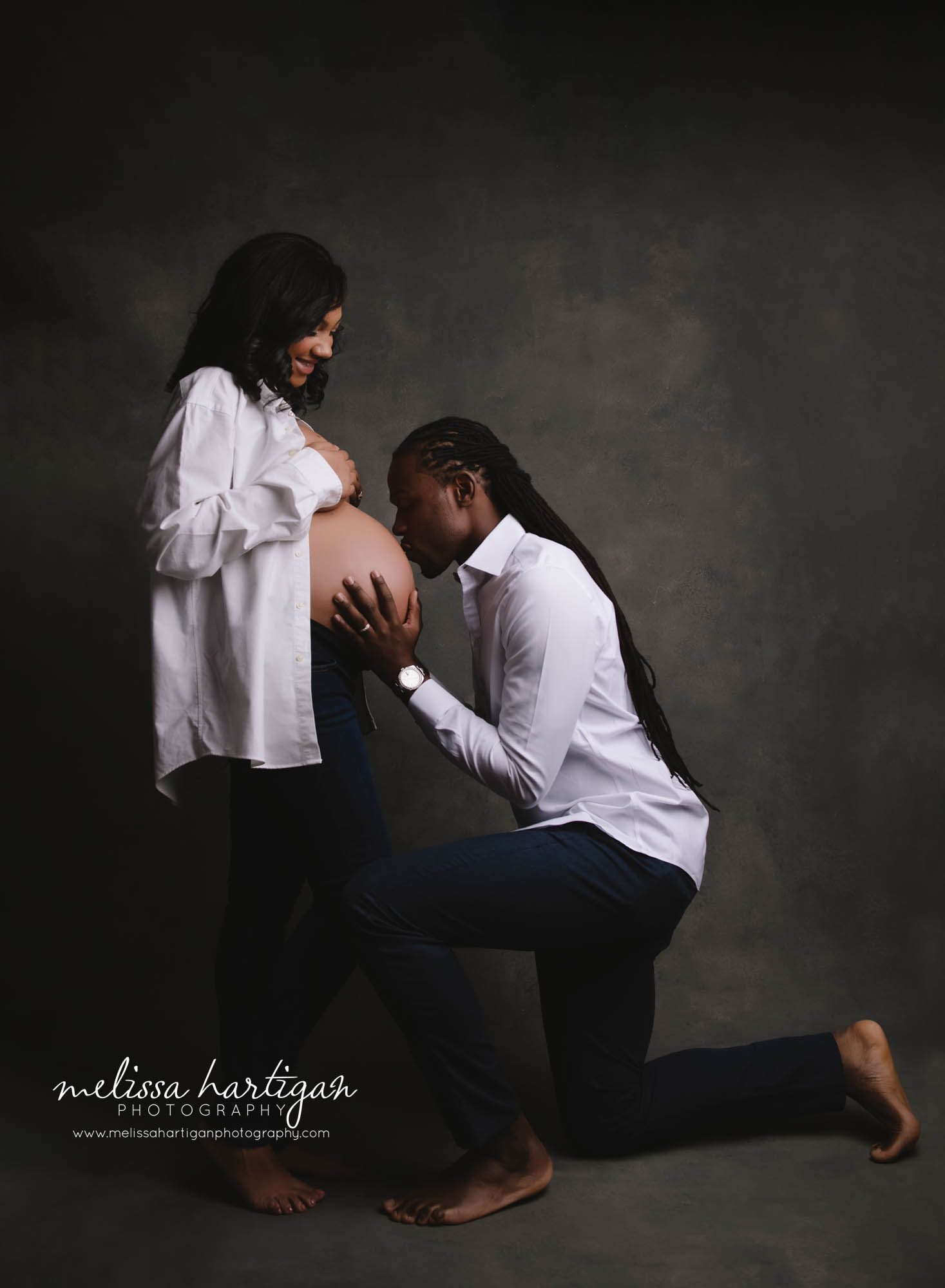 expectant mom and dad studio maternity session dad kissing baby bump